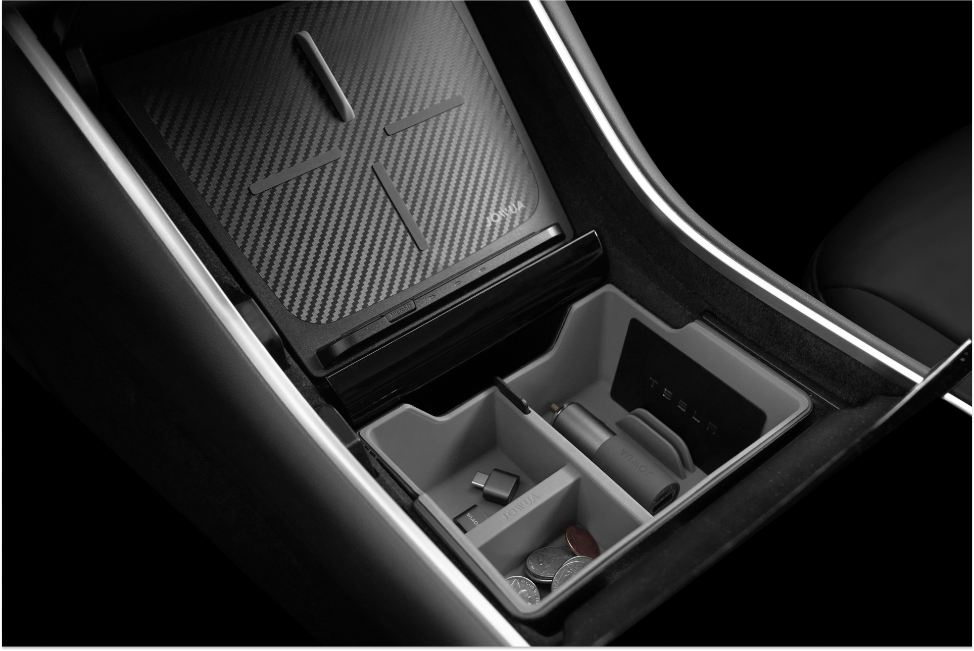 汽車中控台整理器,帶有存放硬幣、USB 驅動器和其他小物品的隔間,旁邊是碳纖維飾面的無線充電板。.
