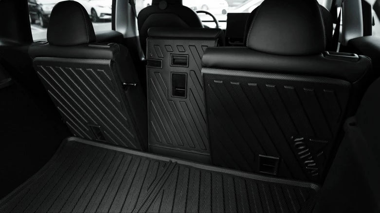 汽車後排座位的視圖,其中一個座位折疊下來,另一個座位直立,顯示後車廂空間和內部細節的黑色內飾。.