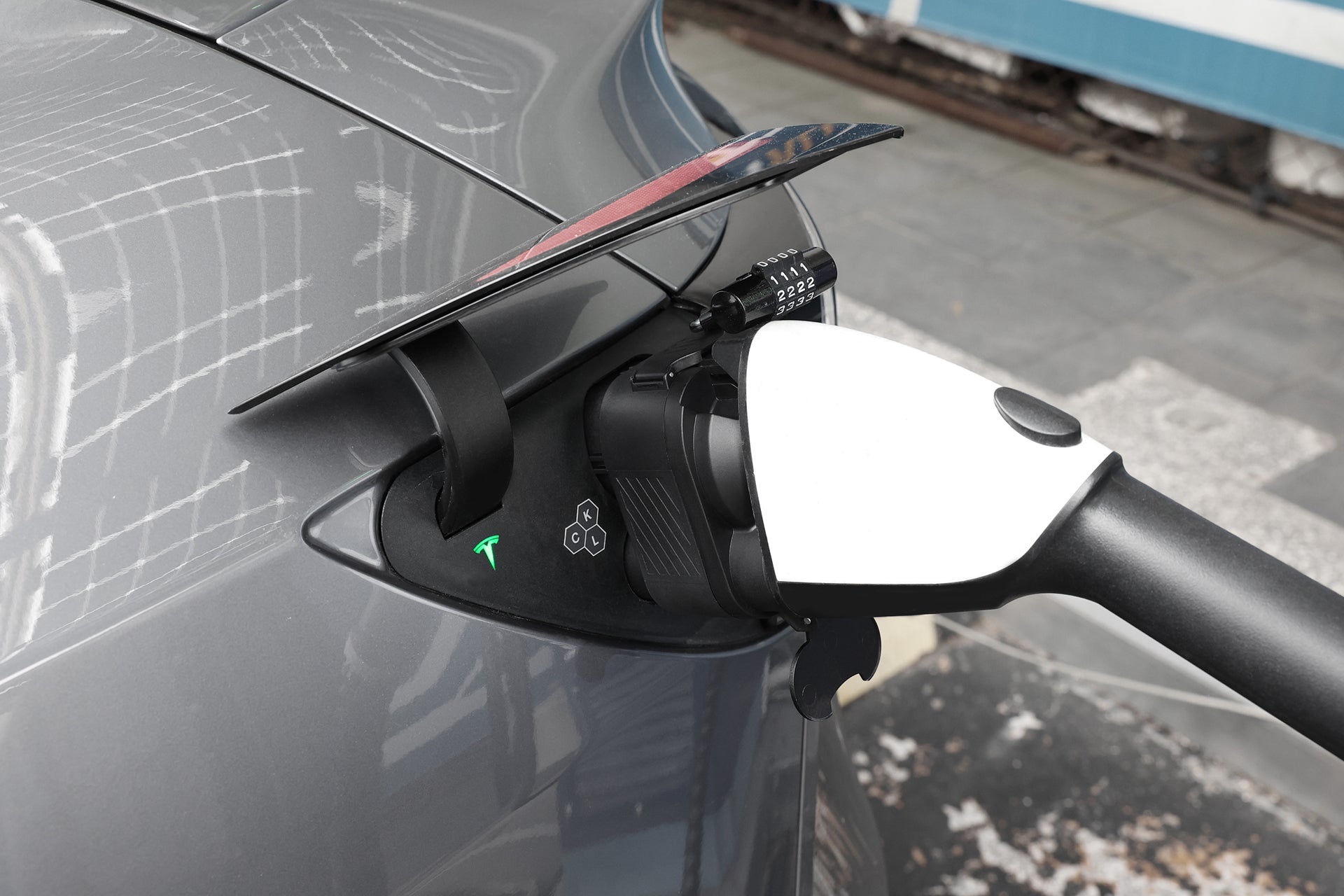 一輛白色特斯拉電動車正在充電的特寫,充電線插入車輛後側的連接埠。.