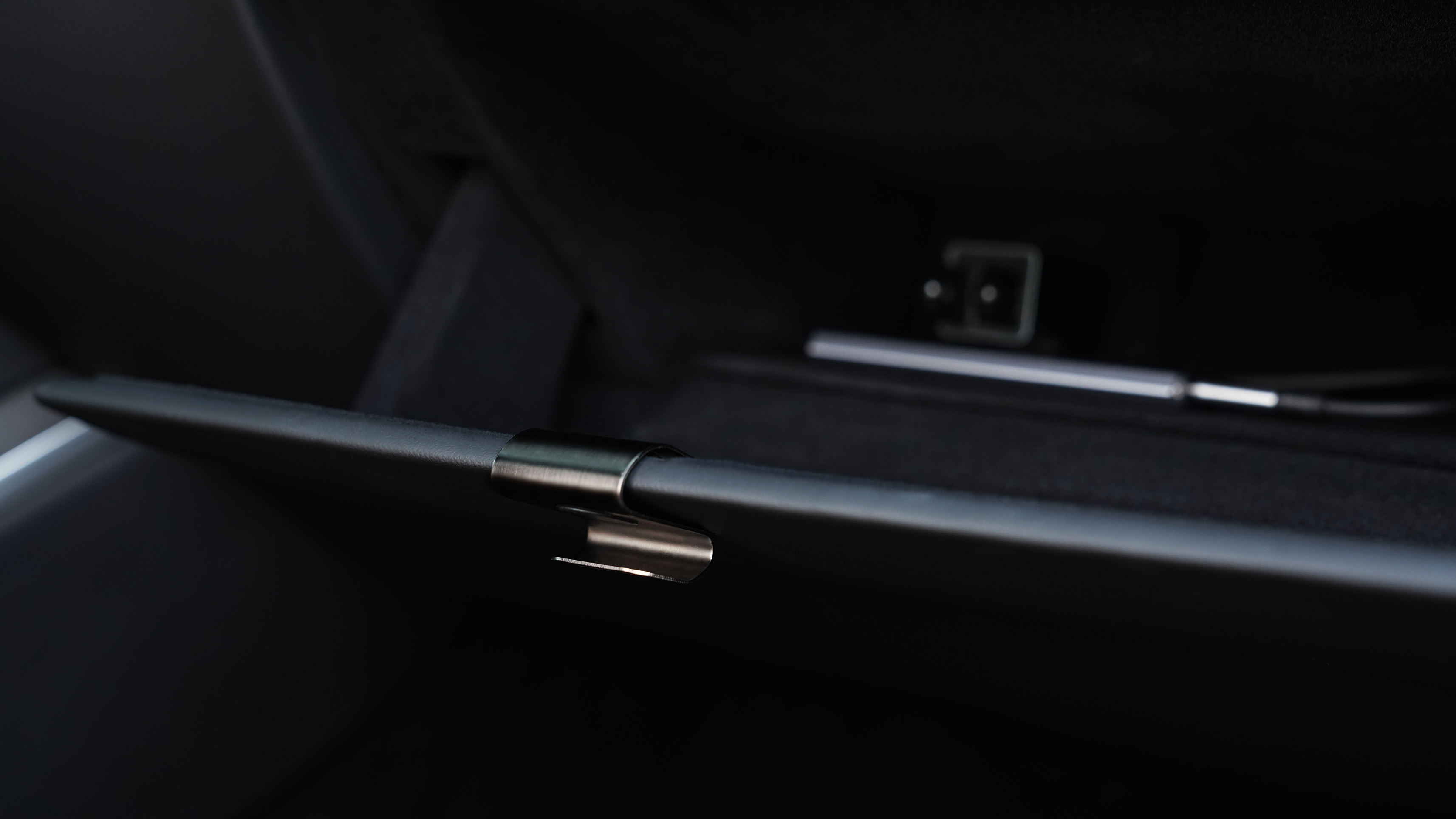 開啟的 Model 3 手套箱特寫顯示內部一片漆黑。門上有一個小金屬把手;裡面放著一支筆和一個帶有可見連接器的電子設備,並配有 JOWUA 台灣手套箱掛鉤(型號 S/X 和型號 3/Y 煥新版)。.