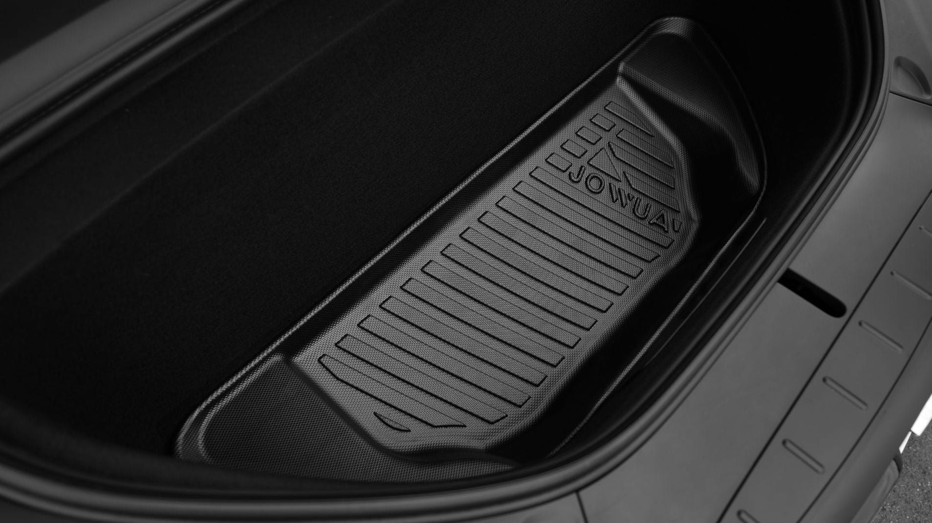 特寫特斯拉 Model X 前行李箱,以黑色羅紋 JOWUA Taiwan 立體防水行李墊廂為特色,在乾淨的深色空間中,展現其優質的全天候保護與品牌浮雕。.