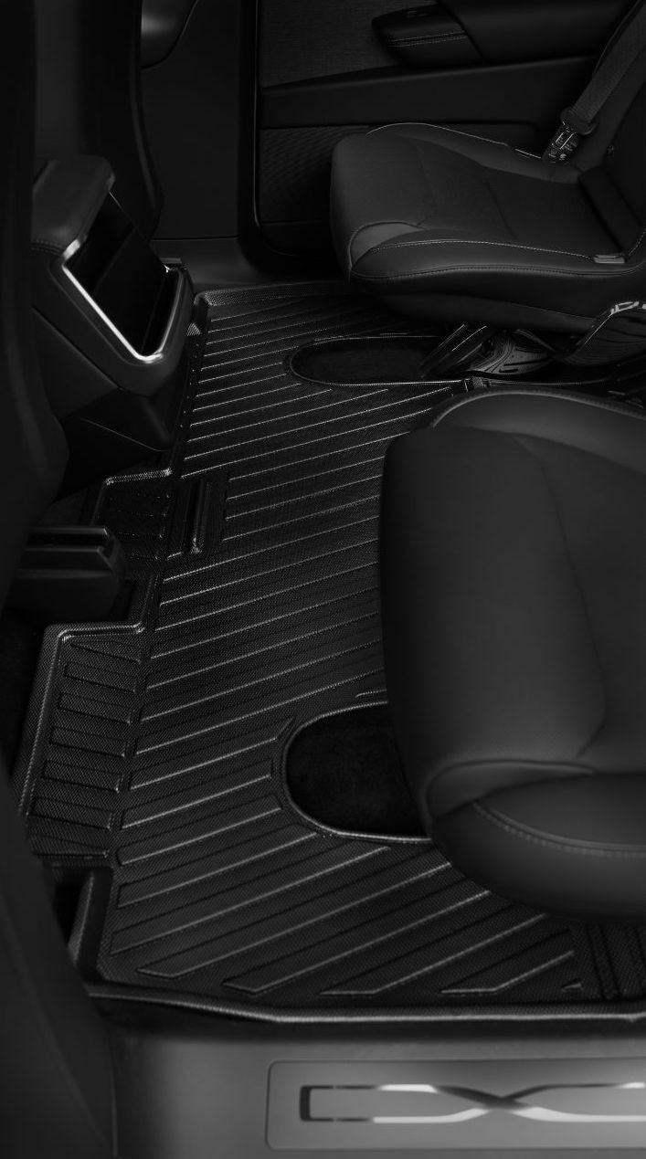Black car interior back seat with dark leather seats and ribbed JOWUA Taiwan 立體防水腳踏墊 (Model X),專利收納設計、全面防護,從上方斜視角拍攝。.