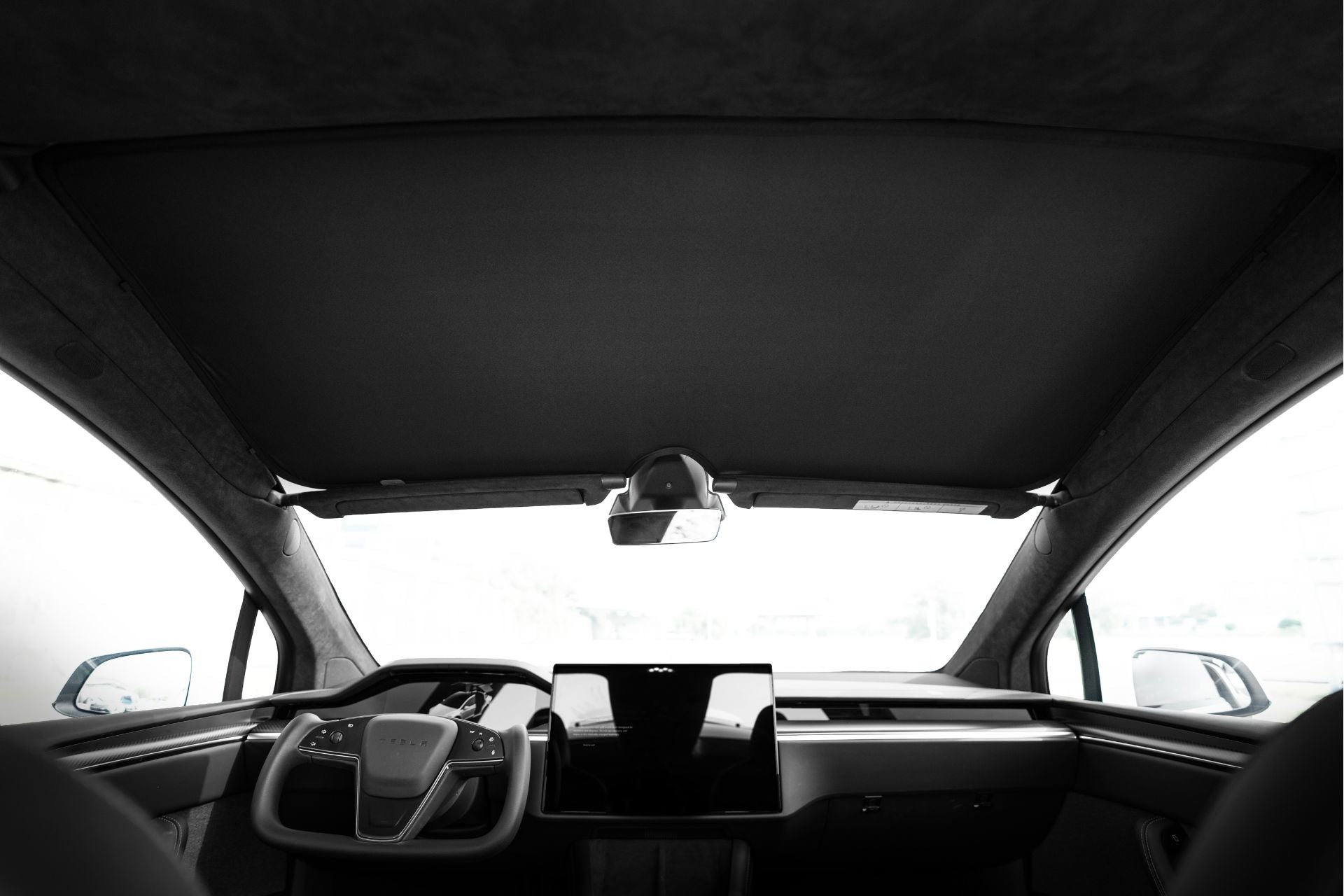 從 Model X 的後座望去,可以看到簡約的內飾,包括時尚的駕駛和乘客座椅。寬大的儀表板在全景天窗下顯示大型觸控屏,採用 JOWUA 台灣玻璃車頂遮陽簾,凸顯現代優雅和功能性。.