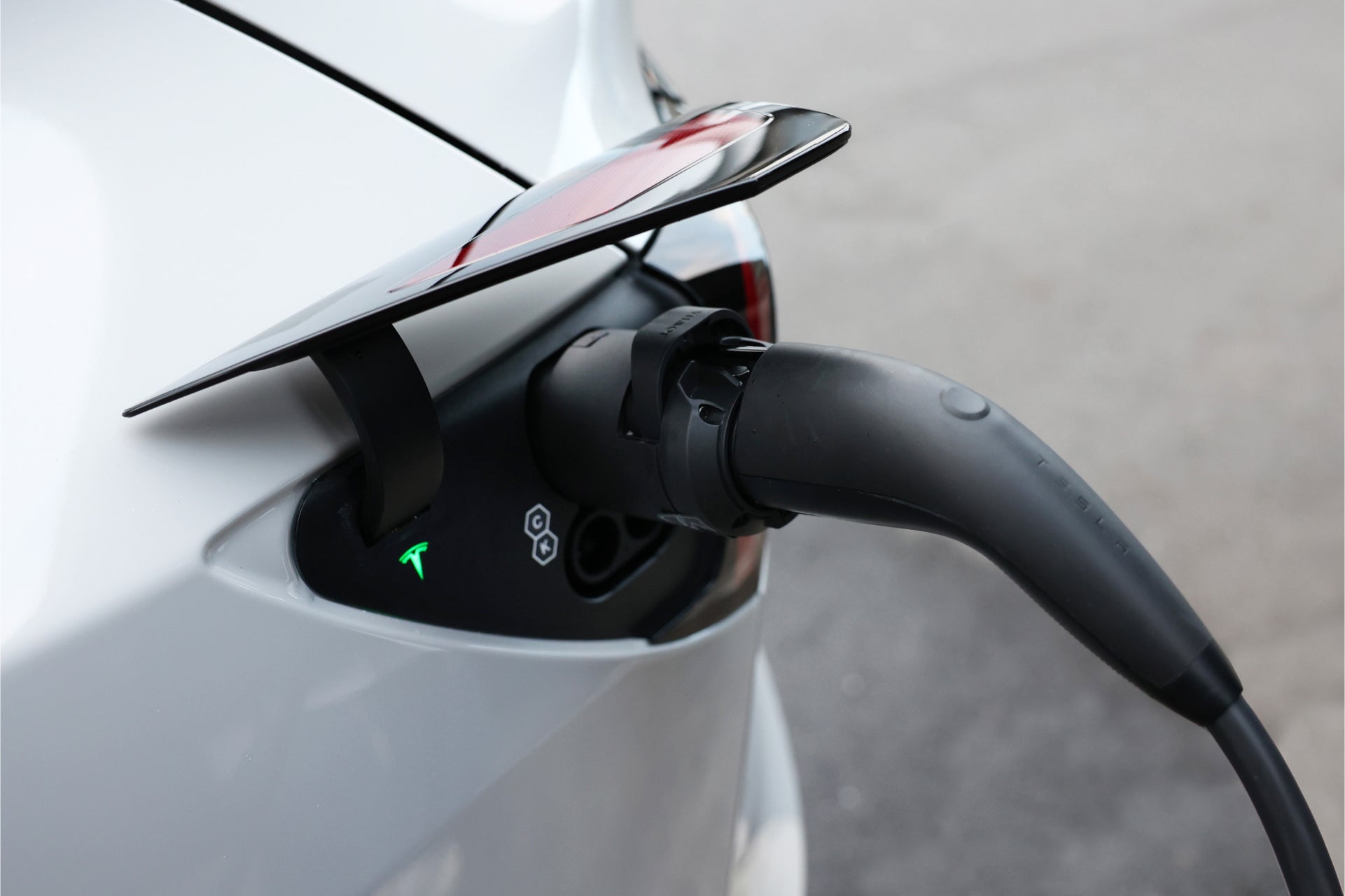 台灣 JOWUA CCS2 快慢充萬用組(通用版)特輯。使用黑色電纜為電動車充電;CCS2 轉接頭已插入,充電埠附近有綠燈和 Tesla 標誌。.