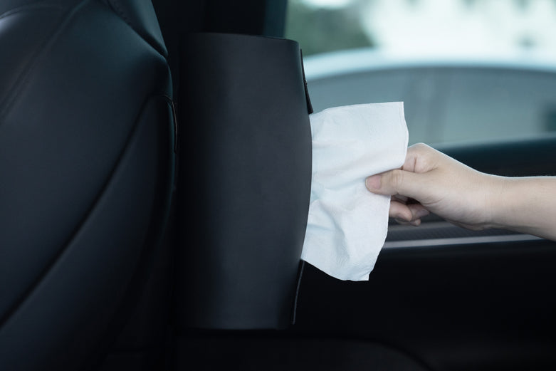 一隻手從 Model Y 椅背上的黑色支架中抽出紙巾,而在車內-JOWUA 台灣的 MagSafe 磁吸掛鎛組 (Model S/X/Y 煥新版) 可在使用 MagSafe 配件或享受車載充電時,方便取用必需品。.