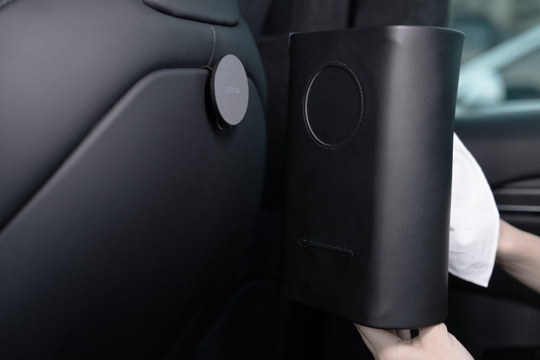 一個人使用iPhone MagSafe磁吸將JOWUA台灣MagSafe磁吸掛鉤組(Model S/X/Y煥新版)連接到Model Y椅背上,與汽車現代簡約的內裝無縫融合。.