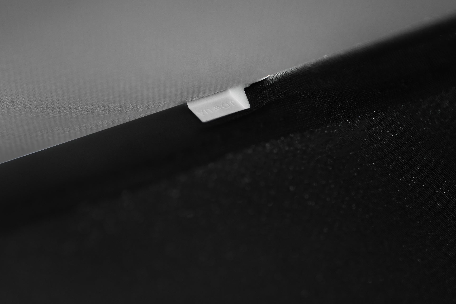 黑色和灰色布料特寫,帶有白色 MONITOR 標籤,是 JOWUA 台灣 Model Y 2021-2024 全車終極防曬組合的一部分,具有抗紫外線防曬功能。.