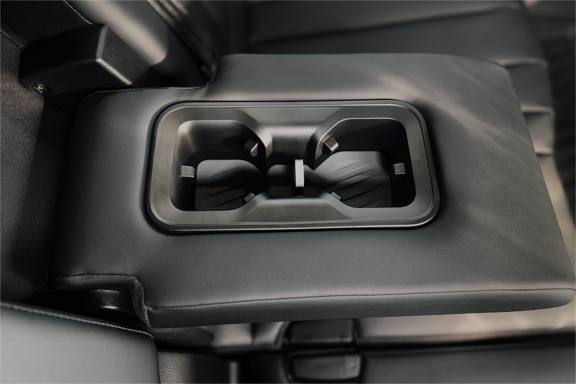 內裝採用黑色真皮扶手,配備JOWUA台灣杯架組(LUXGEN n⁷、n⁷ LR),增強功能性。座椅和區域也是黑色的,體現了 Luxgen n⁷ 現代時尚的汽車配件概念。.