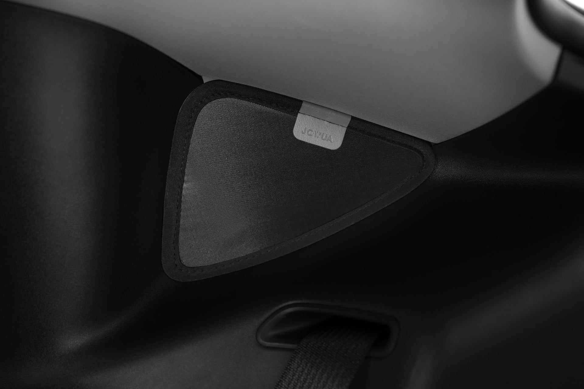 Model Y 黑色和灰色內部細節的特寫,配有標籤的紋理三角形面板。下面的帶子暗示了安全帶機構的一部分或JOWUA台灣側窗+尾門遮陽簾(型號Y)可能連接的位置,以方便使用。.