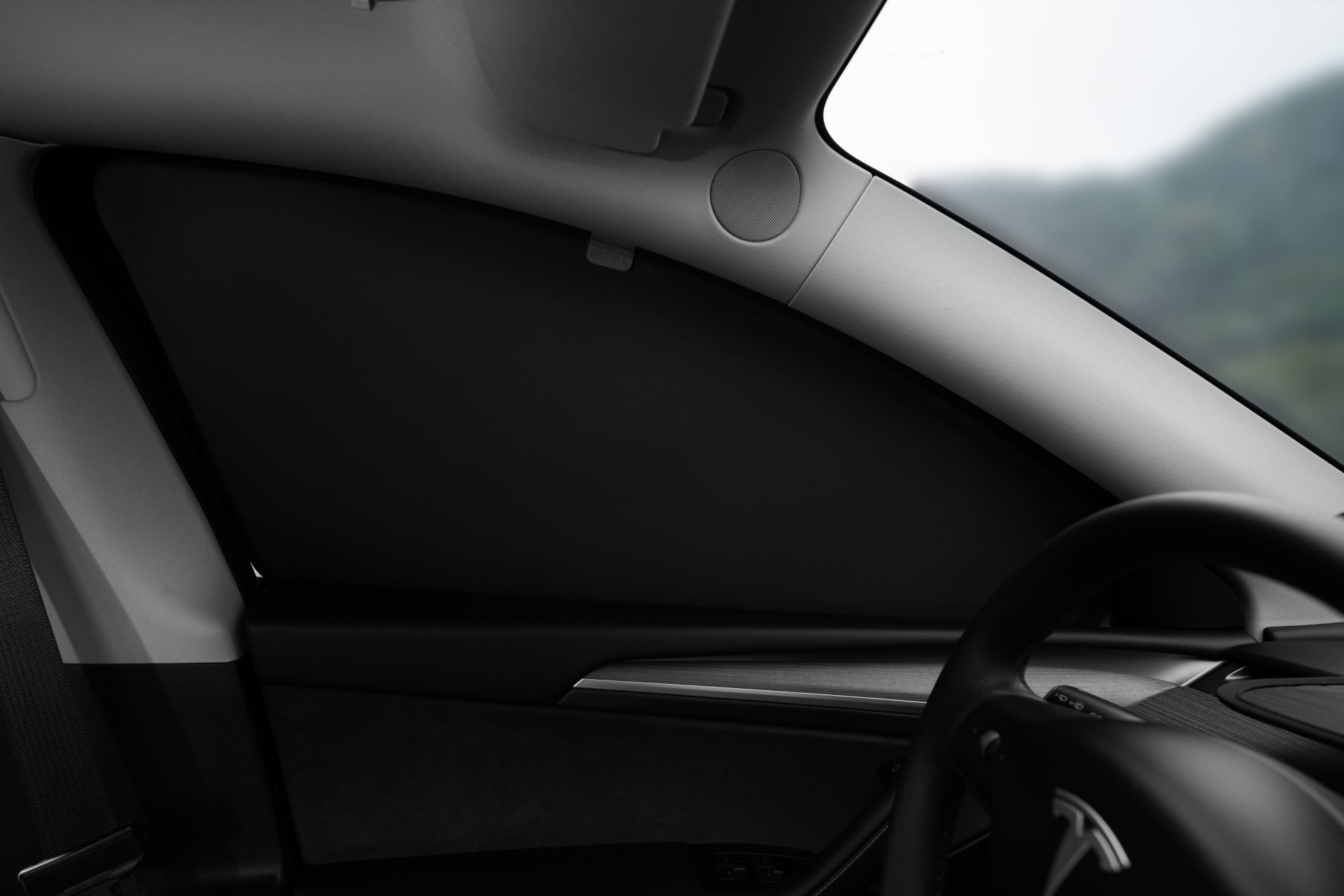 Model Y 前左側內裝特寫,JOWUA Taiwan 全車終極遮陽組合 (Model Y 煥新版 2025+/2021-2024) 覆蓋三角側窗,提供抗 UV 防曬保護。方向盤和儀表板部分可見。.