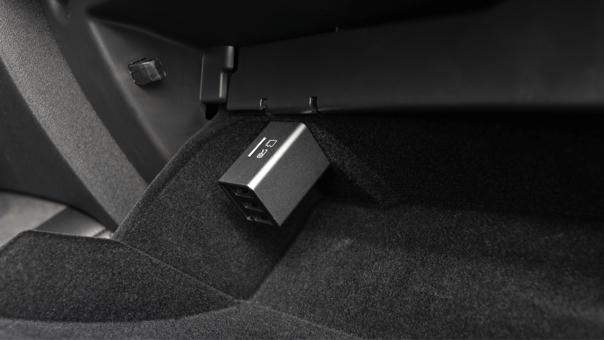 JOWUA Taiwan 無線充電雙搖桿組合 (Model 3/Y) 的特寫畫面,這是一款附有 USB 連接埠的時尚黑色裝置,插在鋪有深色地毯材質的汽車手套箱中。.