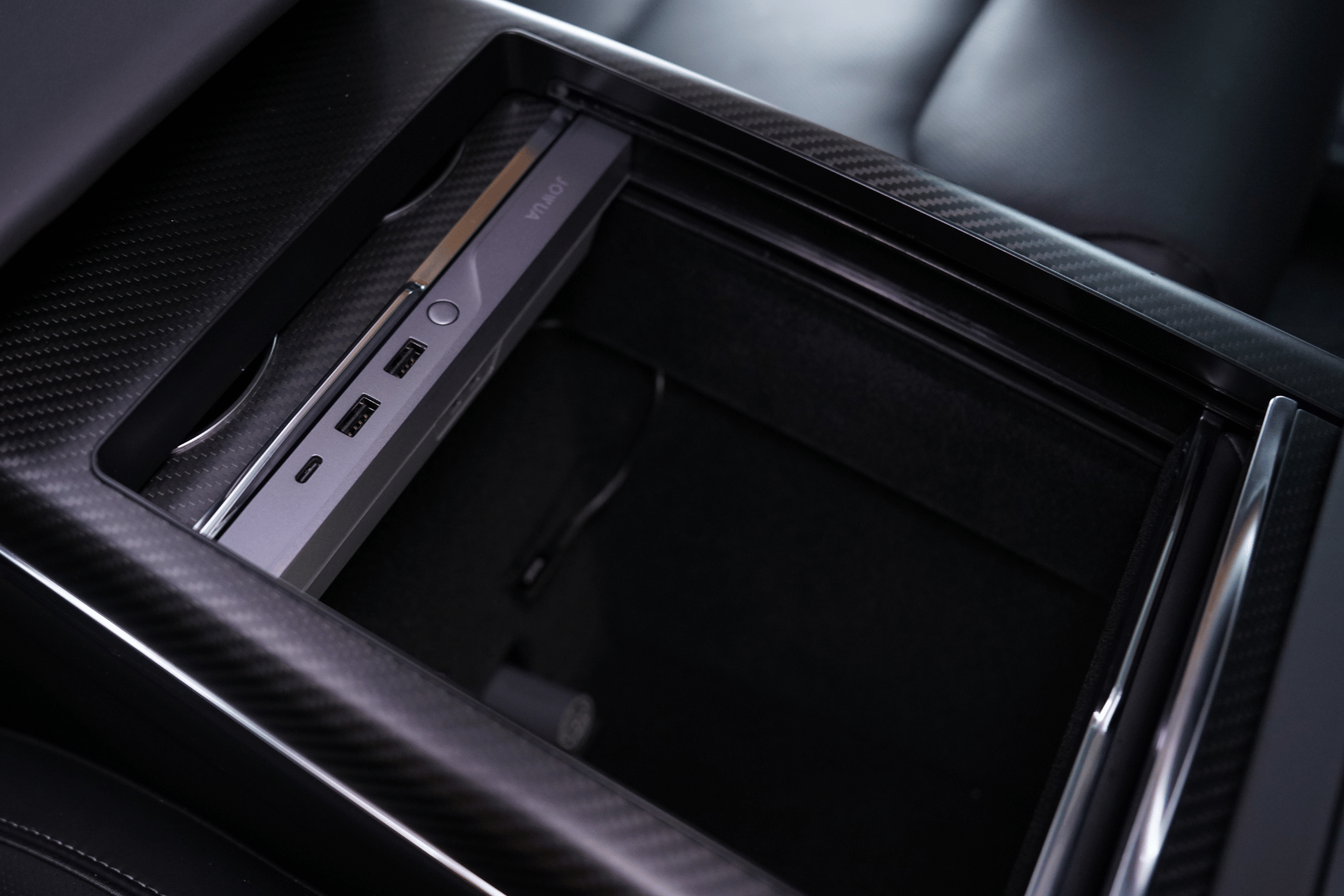 JOWUA Taiwan LED HUB for Tesla Model S/X 中控台特寫,具備 27W PD 快速充電的 USB 埠、輔助埠、黑色碳纖維飾邊與真皮內裝。.