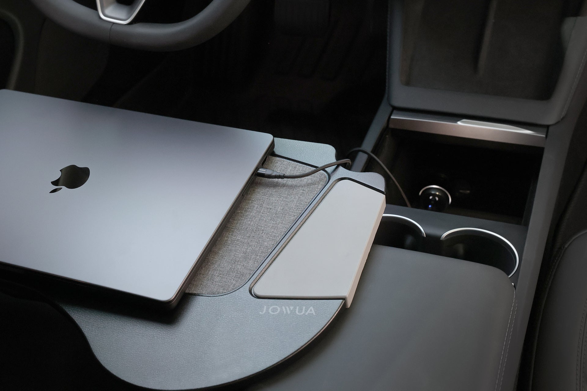 汽車中控台上連接著纖薄外部設備的封閉式 MacBook,突顯了 JOWUA 台灣 165W PD3.1 高效車充,可實現與 PD3.1 快充協定相容的高效充電。.