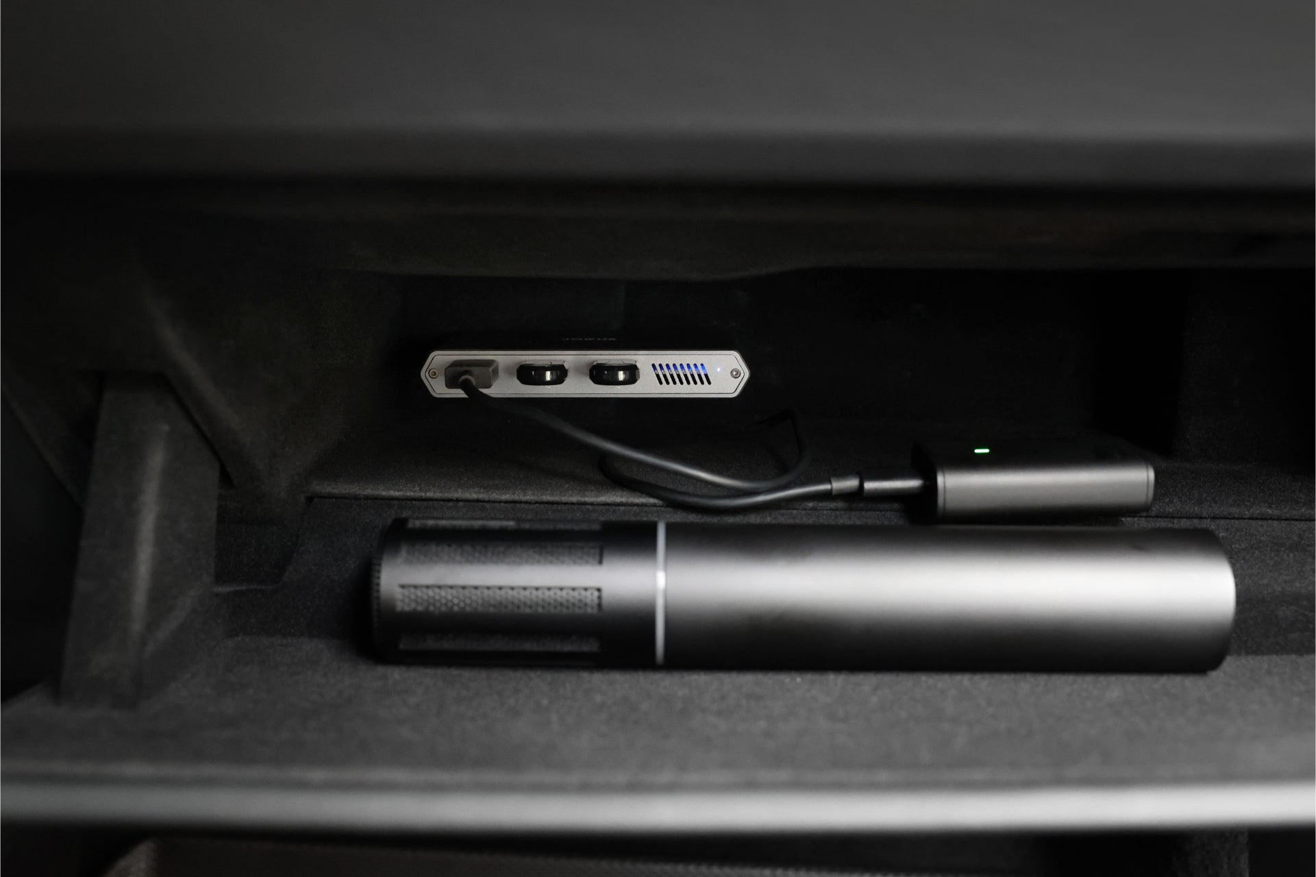 儀表板艙內裝有JOWUA台灣特斯拉專用1TB SSD+3連接埠HUB,附USB連接埠和電纜,以及一個圓柱形黑色物體。它內襯採用柔軟的深色材料,非常適合希望增強 2024 年以上車型和 Cybertruck 駕駛體驗的 Tesla 車主。.