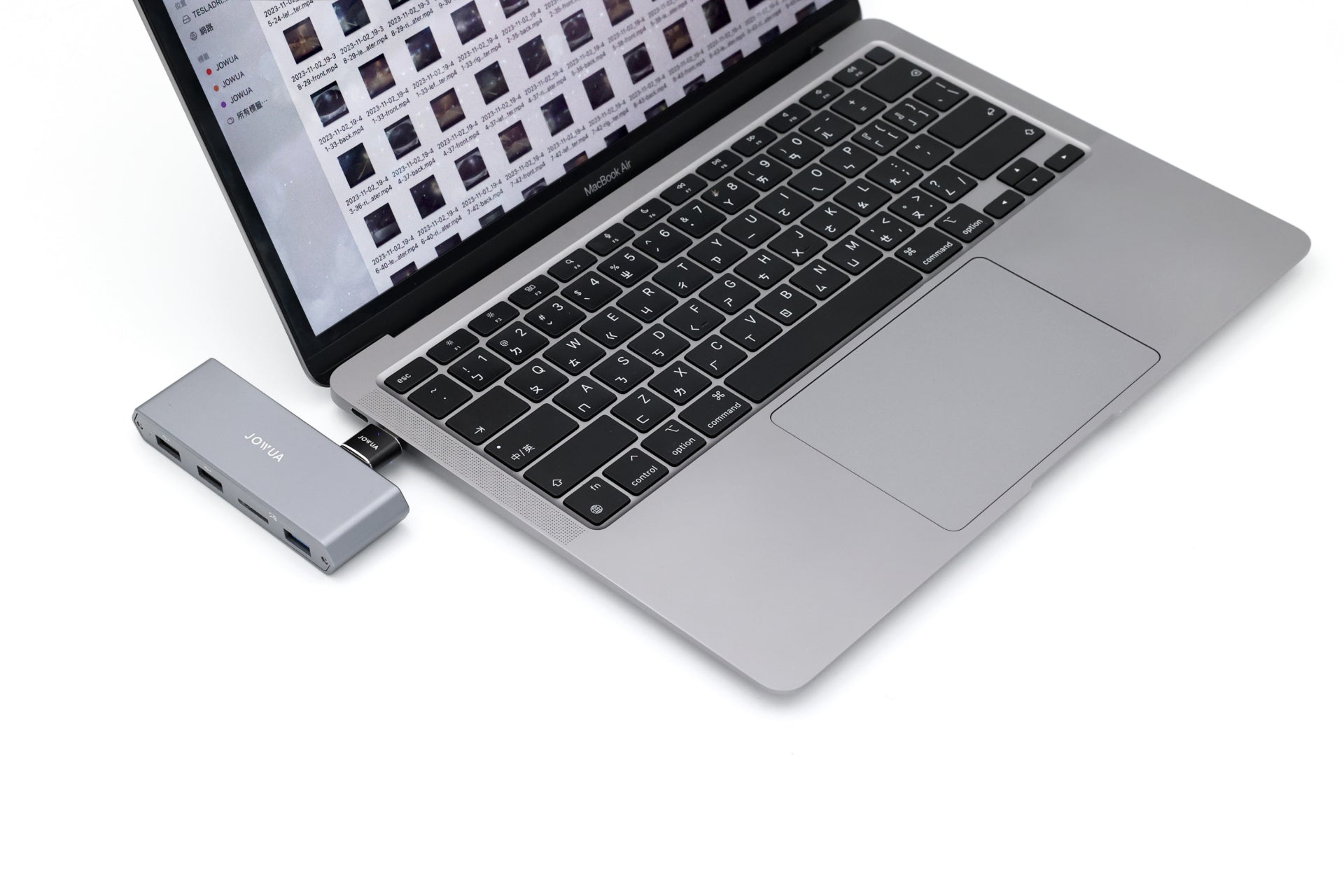 白底銀色筆記型電腦,連接台灣 JOWUA 的 Tesla 雙用儲存 HUB (讀卡器 & 原廠 USB)。螢幕可顯示影像縮圖,HW4.0 相容性可確保無縫連接。.