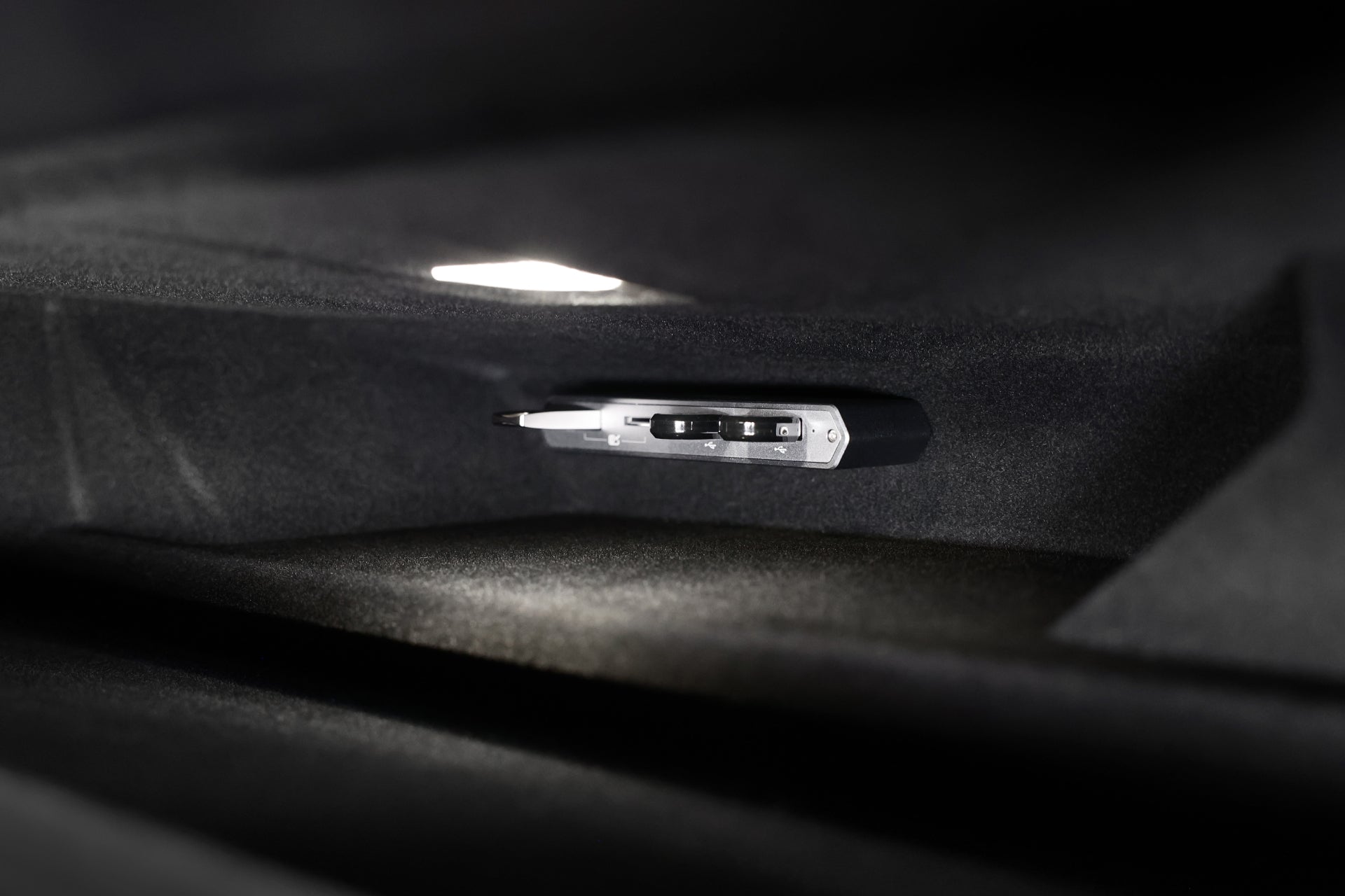 特斯拉車內照明雜物箱特寫,展示 JOWUA Taiwan Tesla 雙用儲存 HUB (讀卡器 & 原廠 USB) for Model S/X/3/Y煥然一新版/Cybertruck,與時尚的黑色內飾無縫整合。.