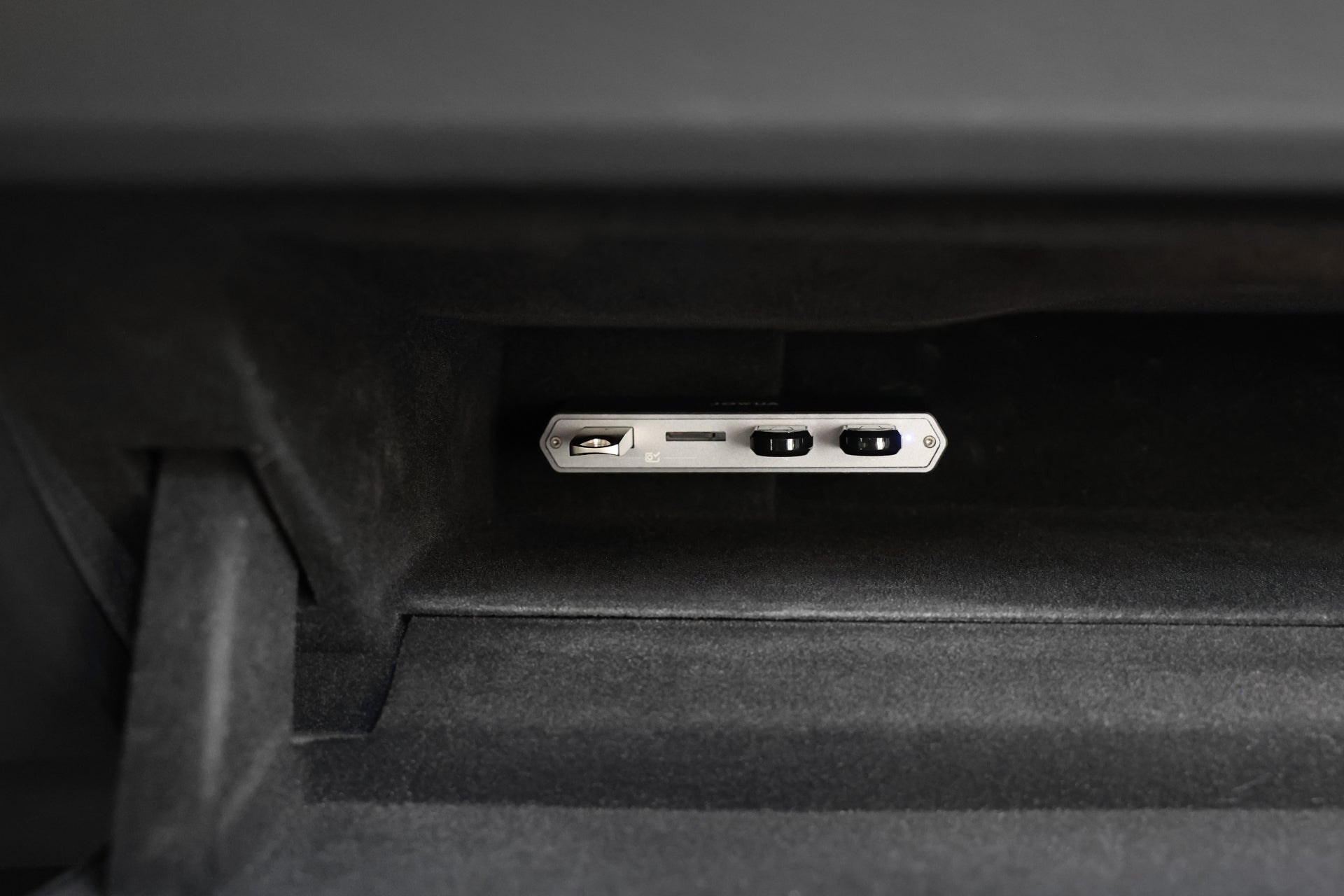 特斯拉手套箱的特寫,內含適用於 Model S/X/3/Y 煥然一新版/Cybertruck 的 JOWUA Taiwan Tesla 雙用儲存 HUB (讀卡器 & 原廠 USB)--一個有按鈕和插槽的長方形裝置,內置讀卡器和 USB 集線器。.