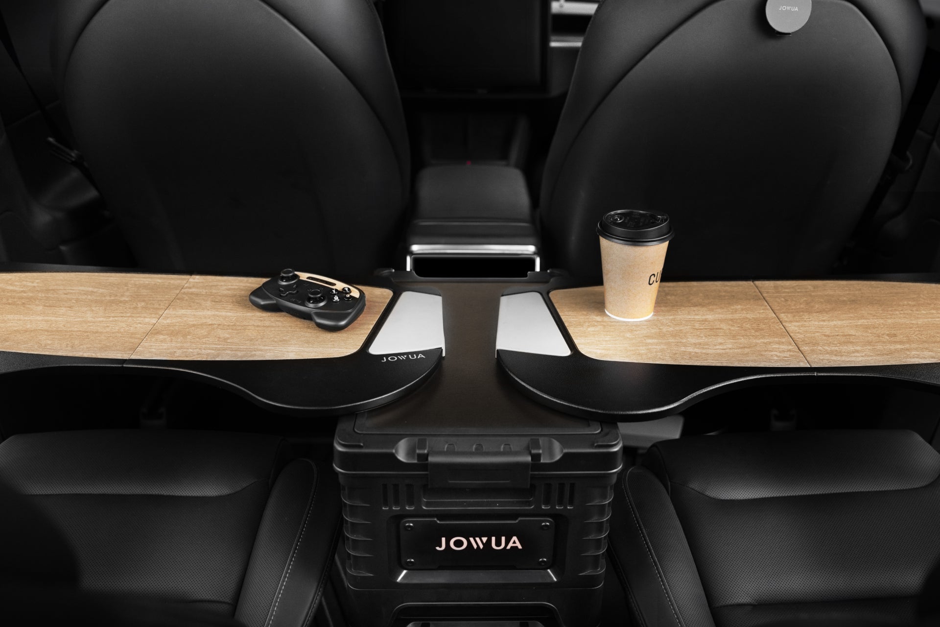 Model X 的內裝採用木質中控台,並配有 JOWUA 台灣車用折疊桌板。遊戲控制器和咖啡杯整齊地放置在頂部,而黑色皮革座椅增強了魔術大空間的感覺。.