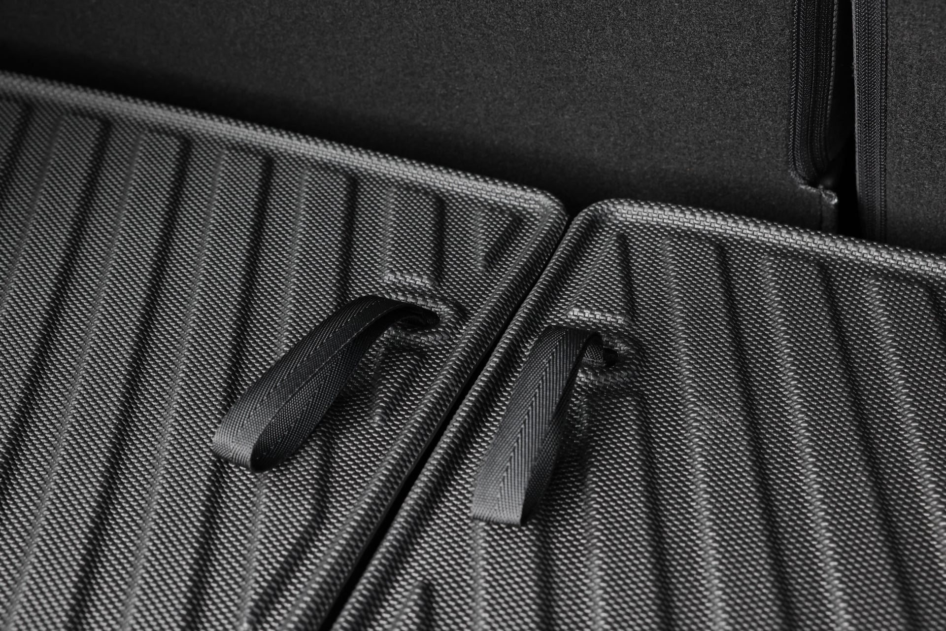 兩張深灰色汽車椅背特寫,搭配黑色拉帶,呈現表面紋理與接縫,加上部分 JOWUA Taiwan 立體防水行李廂墊+椅背墊組合 for LUXGEN n⁷ 7人座。.