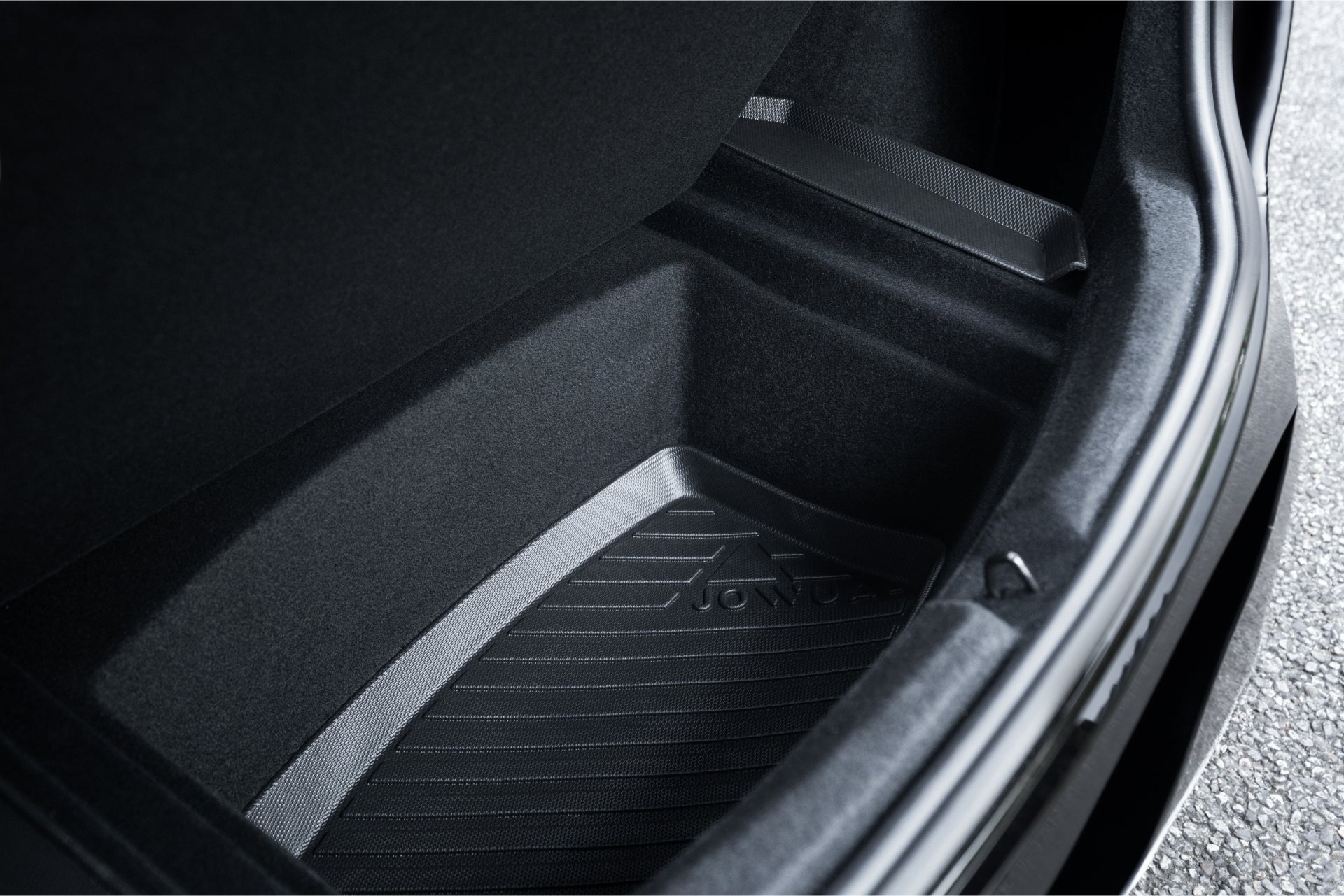 特斯拉 Model 3 2024+煥新版 JOWUA 台灣立體防水行李廂墊後行李箱內裝特寫。它採用黑色和灰色紋理的內襯,帶有便於抓握的脊線和三角形圖案,類似於升級版的防水行李箱墊。.