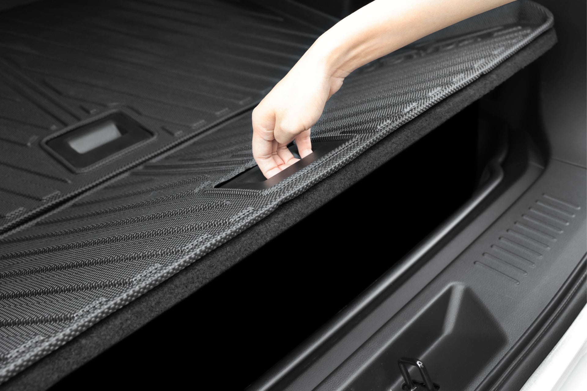 用手掀開車尾箱的 JOWUA Taiwan 立體防水行李廂墊+椅背墊組合 (LUXGEN n⁷ 5人座),露出下方的儲物空間。簡潔現代的內裝也採用 TPE 防水腳墊,提供額外保護。.
