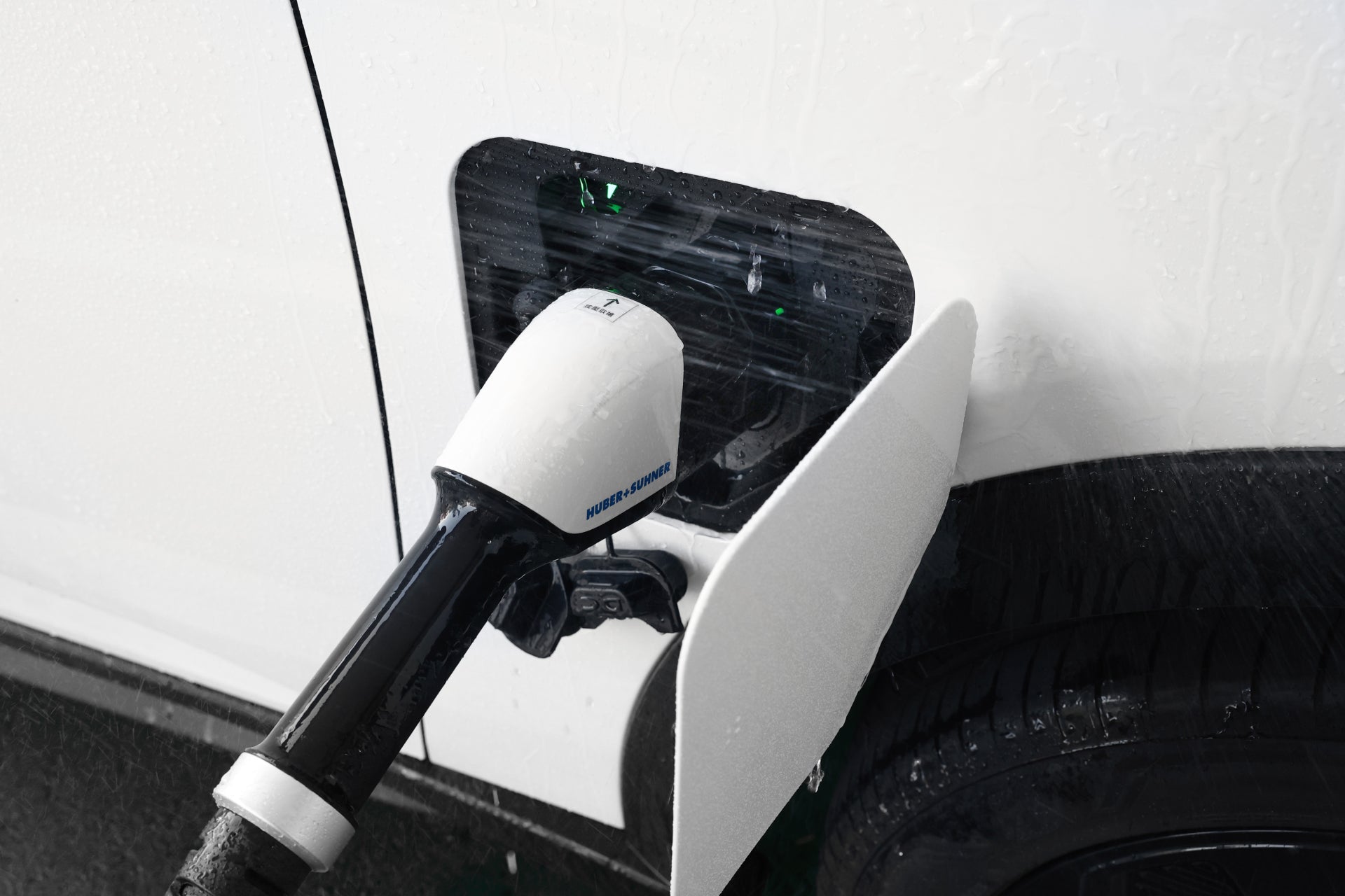 JOWUA 台灣 CCS2 至 CCS1 DC & AC 快慢充轉接頭牢固連接到白色電動車充電埠的特寫。該區域空曠,有水滴暗示要下雨,而溫度監控防護確保安全快速和慢速充電。.