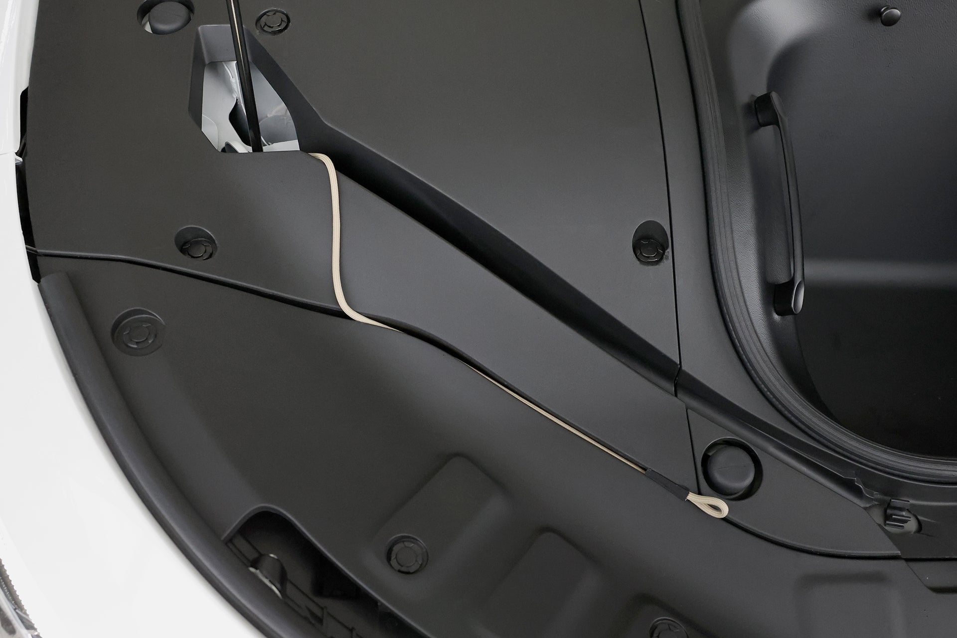 時尚納智捷LUXGEN n⁷上JOWUA台灣充電槍緊急釋放延長拉繩的特寫,展現出黑色設計,周圍是白色面板,帶有可見螺栓和充電槍鎖扣,將簡約美學與實用的電纜管理融為一體。.