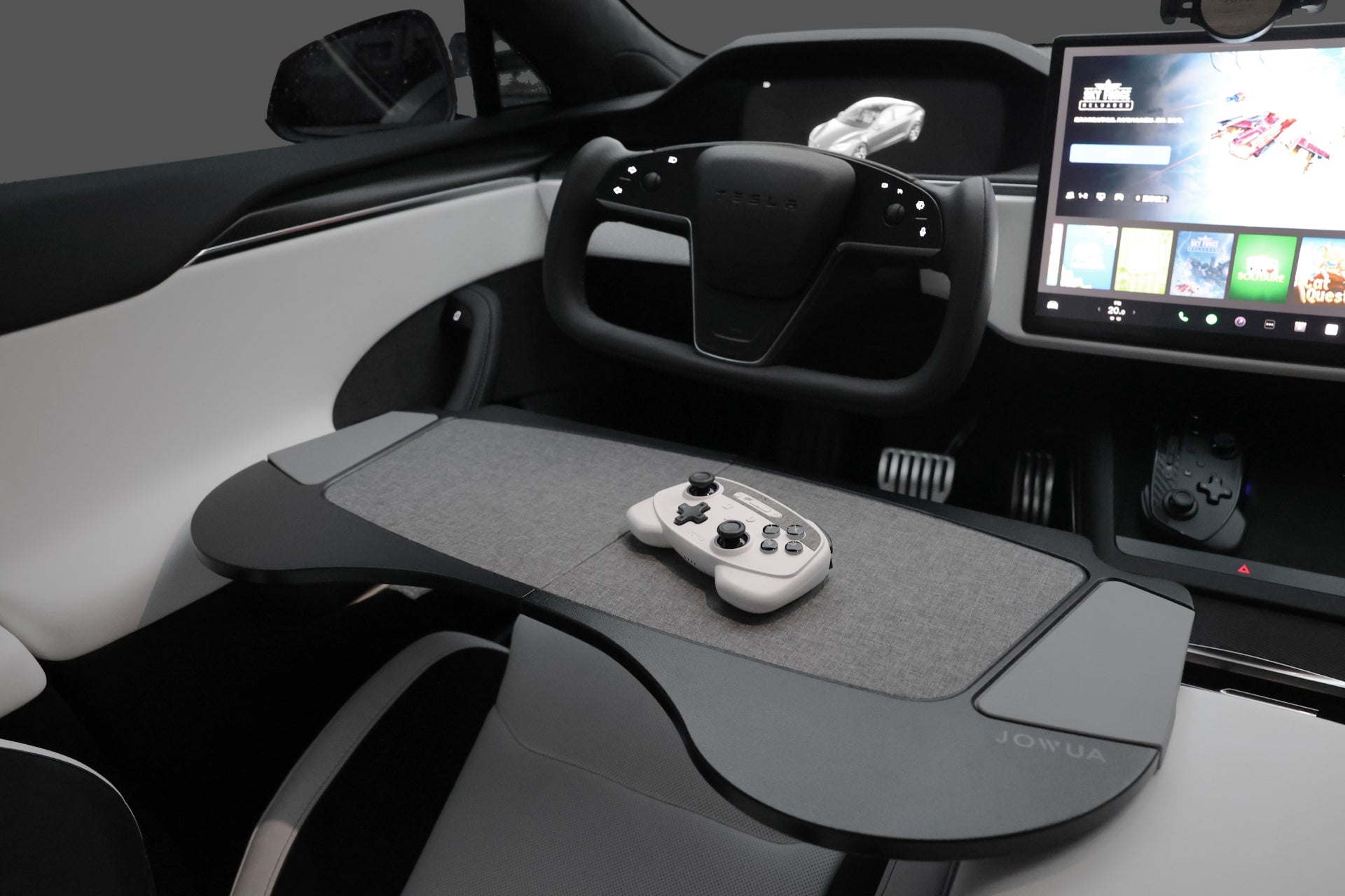 Tesla 內裝搭配 JOWUA 台灣車用折疊桌板兩入組、轉向架、顯示遊戲的大型觸控螢幕以及托盤上的控制器,打造出一個採用折疊式設計的工作和娛樂的行動辦公室。.