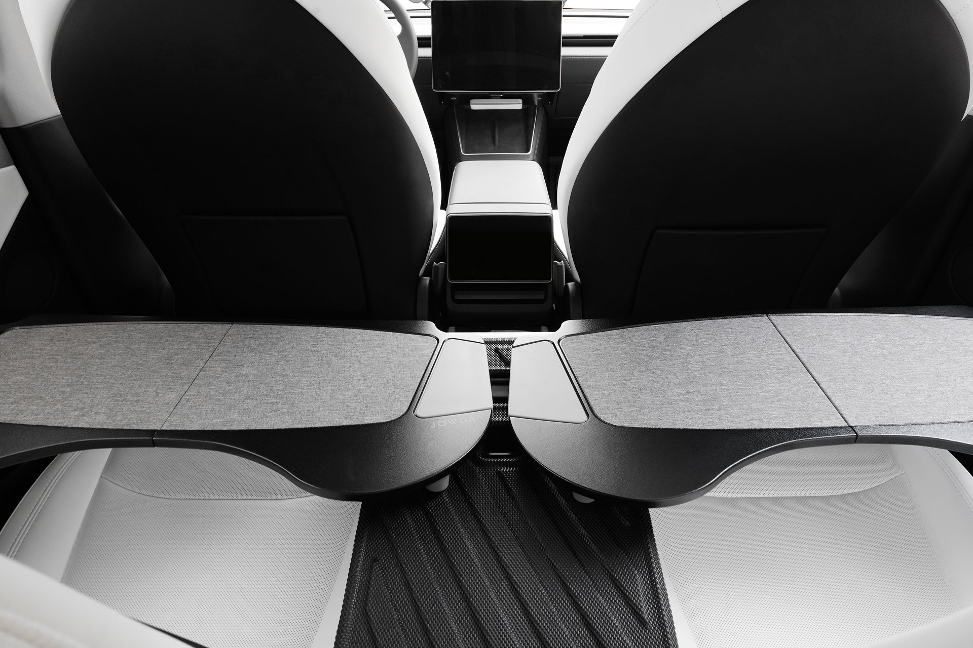 現代特斯拉的內部視圖,兩個前座椅後面配有 JOWUA 台灣車用折疊桌板兩入組,以及一個中控台。黑白簡約的座椅設計營造出時尚的行動辦公室氛圍。.