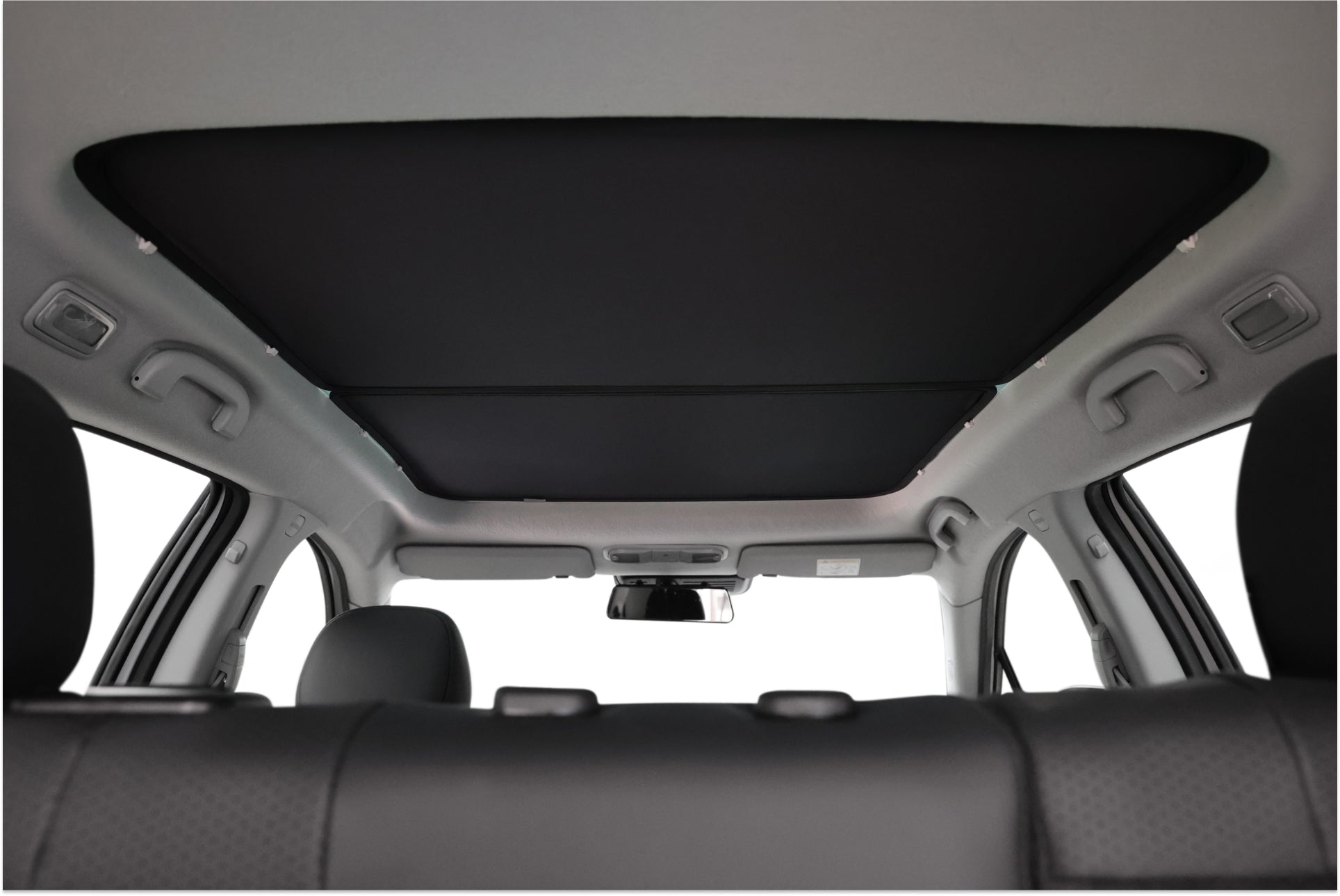 由 JOWUA Taiwan 設計的玻璃車頂遮陽簾的內部視圖呈現關閉狀態,與後座的天花板完美融合。前景中可以看到兩個頭枕,與 LUXGEN n⁷ 等車型的時尚設計相匹配。.