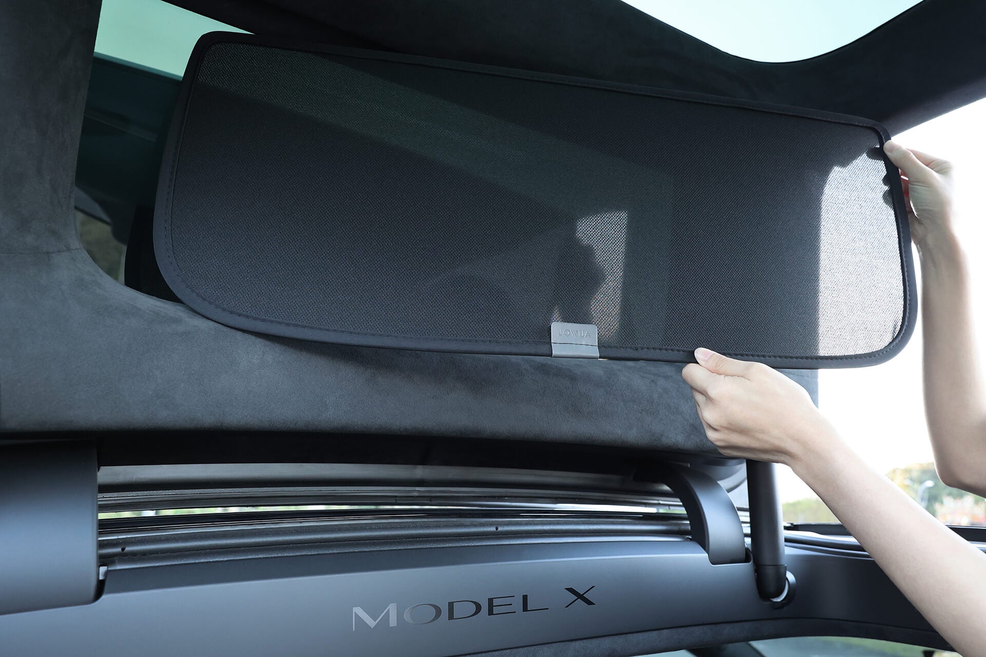 一名人員正在 Model X 2021+ 的全景擋風玻璃上安裝 JOWUA Taiwan 分離式遮陽簾組件,以提供紫外線防護並提升駕駛體驗。.
