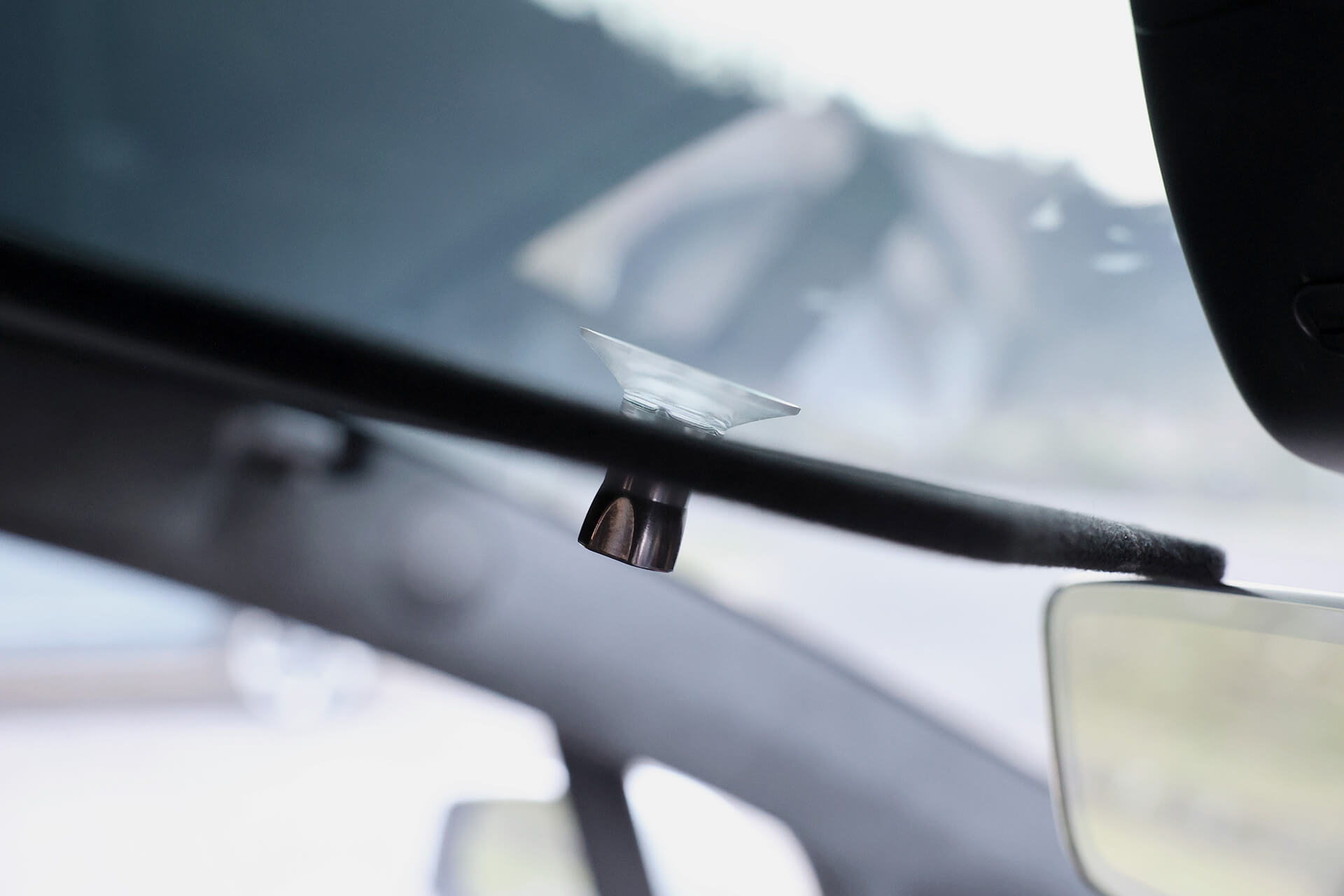 特寫:Model X 2021+ 擋風玻璃內後視鏡附近安裝的一個小透明塑膠掛鉤。背景虛化,暗示了JOWUA Taiwan分離式遮陽簾組合及其有效的紫外線屏蔽設計。.