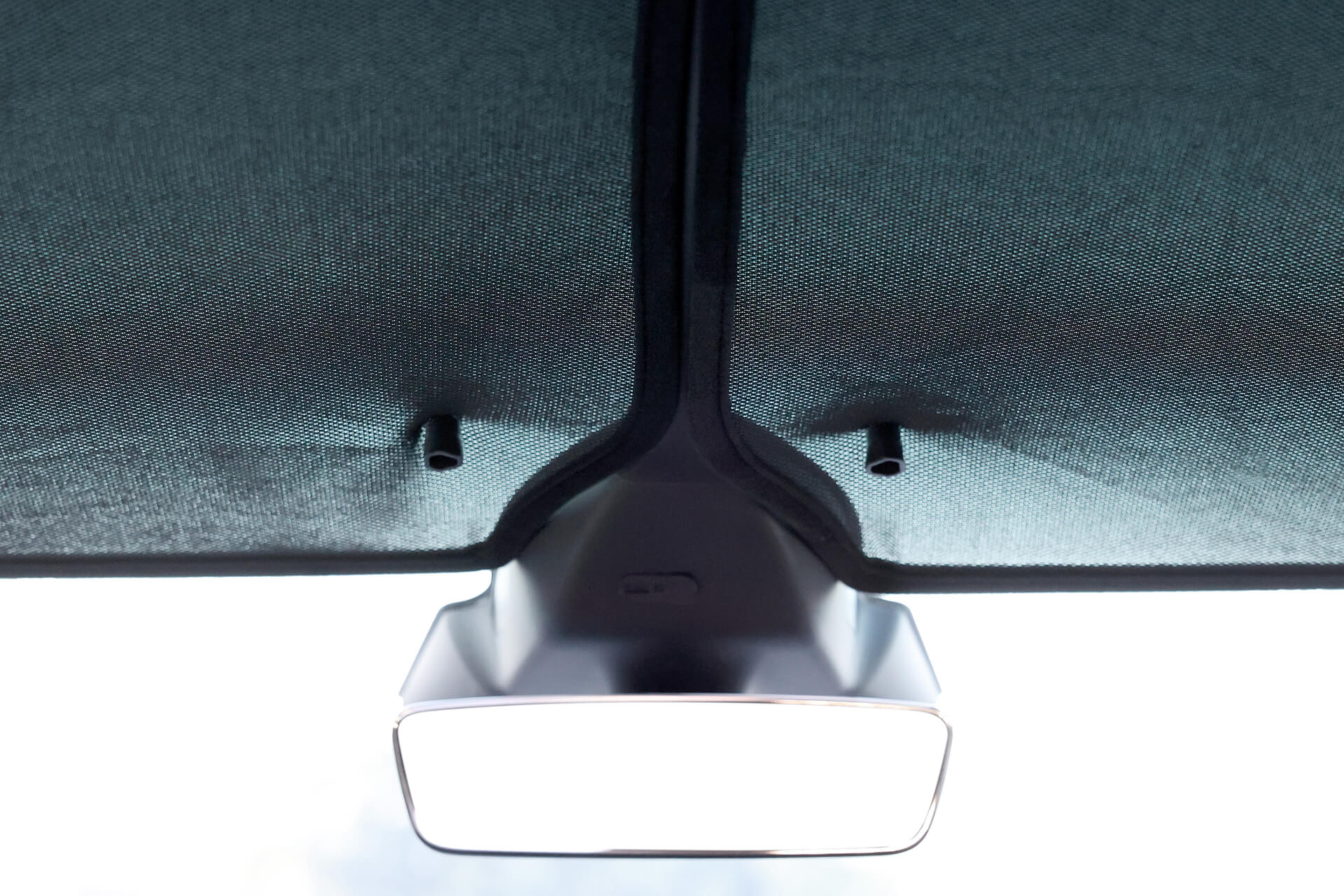 Model X 車內車頂的特寫突顯了後視鏡,並露出了其上方略微分離的紋理織物。兩根小棒體現了JOWUA台灣分離式遮光簾(Model X)先進的隔熱效果。.