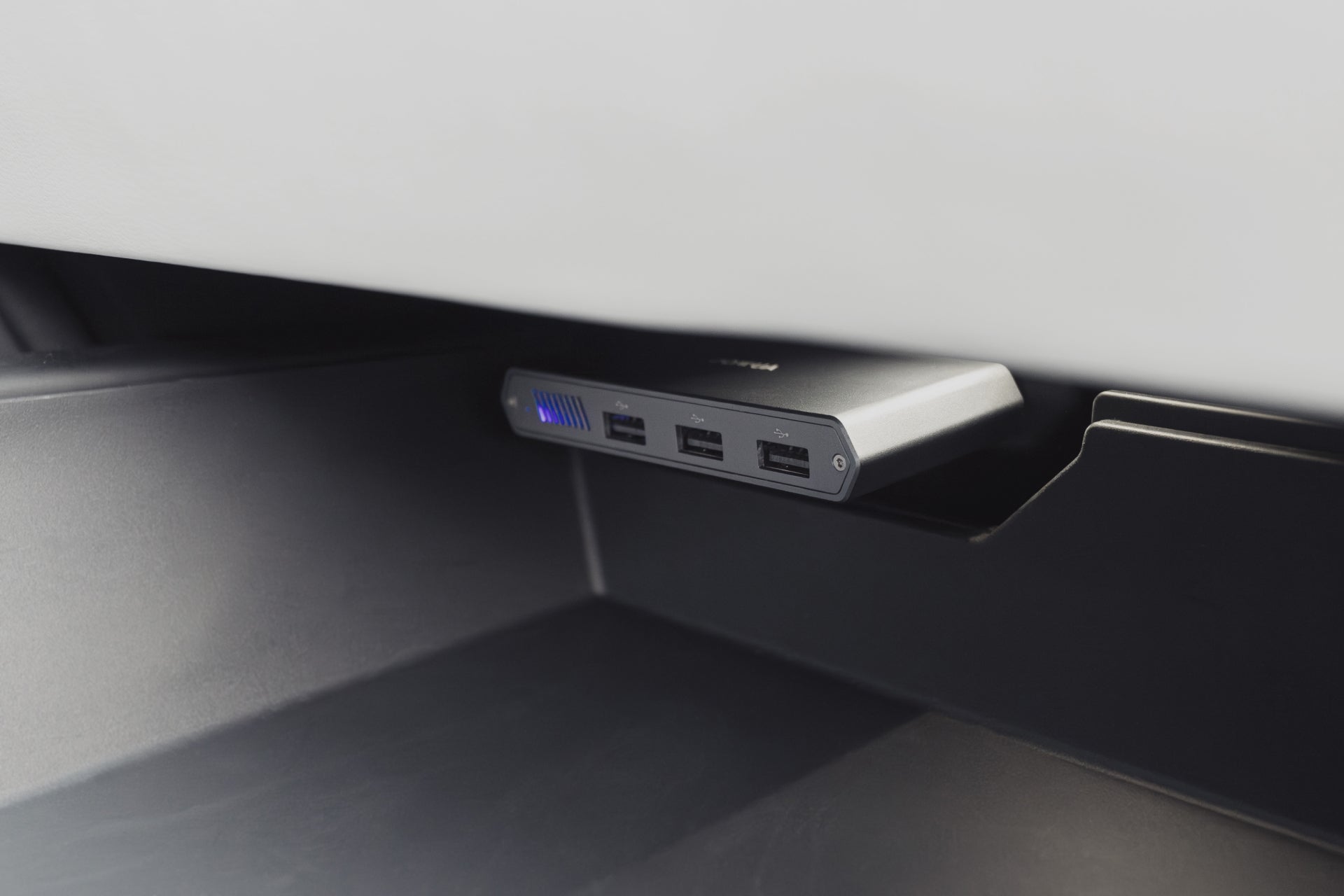已安裝的JOWUA 台灣Tesla 專用1TB SSD+3 端口HUB 的特寫,具有三個USB 端口和一個發光的藍色指示燈,坐落在黑色底座上方的白色表面下,非常適合尋求升級其車內或汽車的Tesla 車主辦公室設置。.