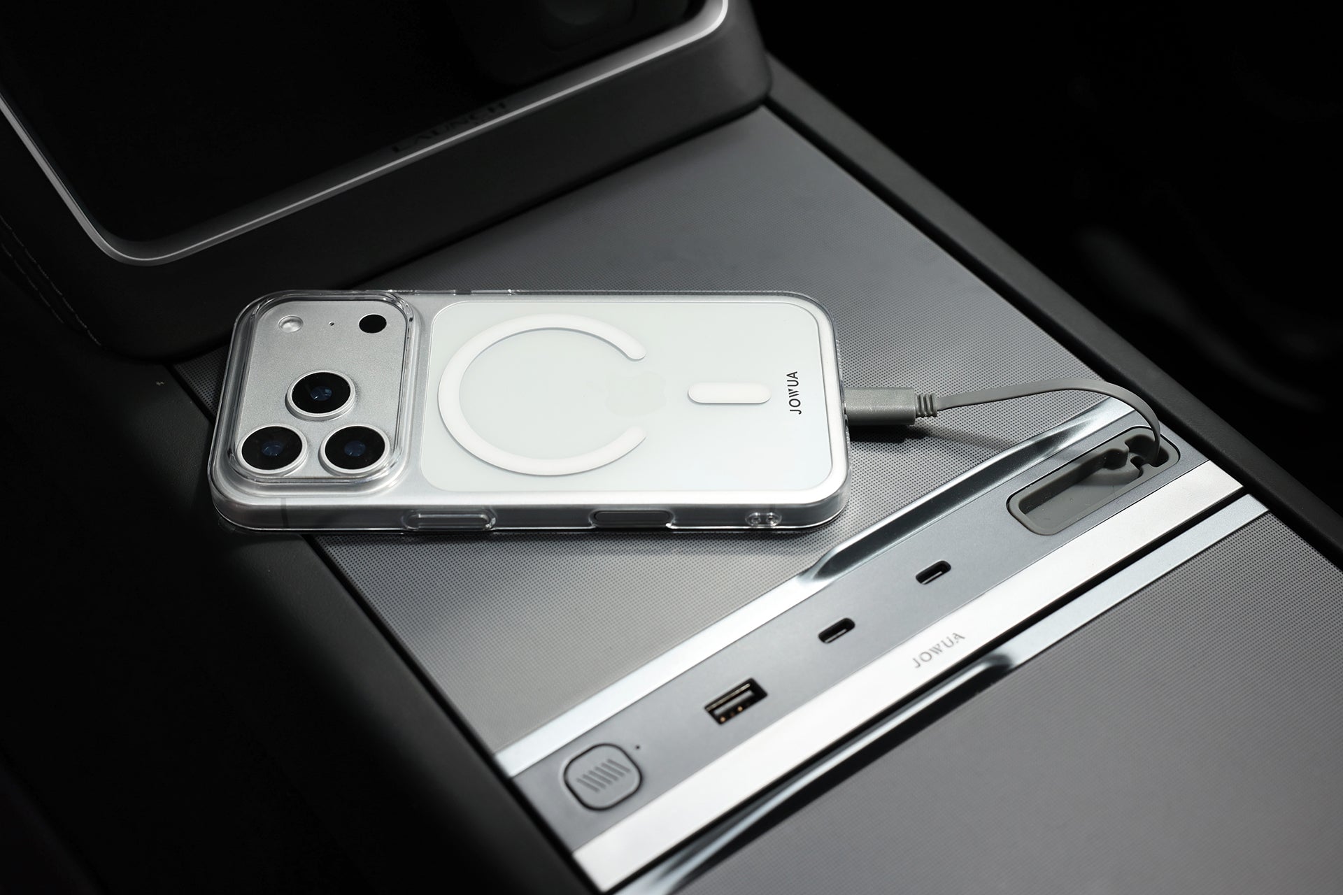 在汽車的中控台上,使用 JOWUA 台灣電墊專案【煥新版|交車禮包】配件,搭配額外的電源和 USB 插座,整齊地將裝有透明保護套的智慧型手機透過電纜線充電。.