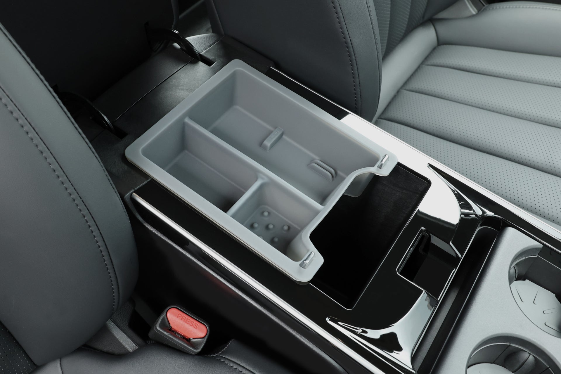 圖片展示了 LUXGEN n⁷ 的內部,其中配備有 JOWUA 台灣扶手箱收納盒,展示了其雙層設計,具有多個隔間和可拆卸托盤。它還突出了黑色皮革座椅和紅色安全帶扣,以增加精緻感。.