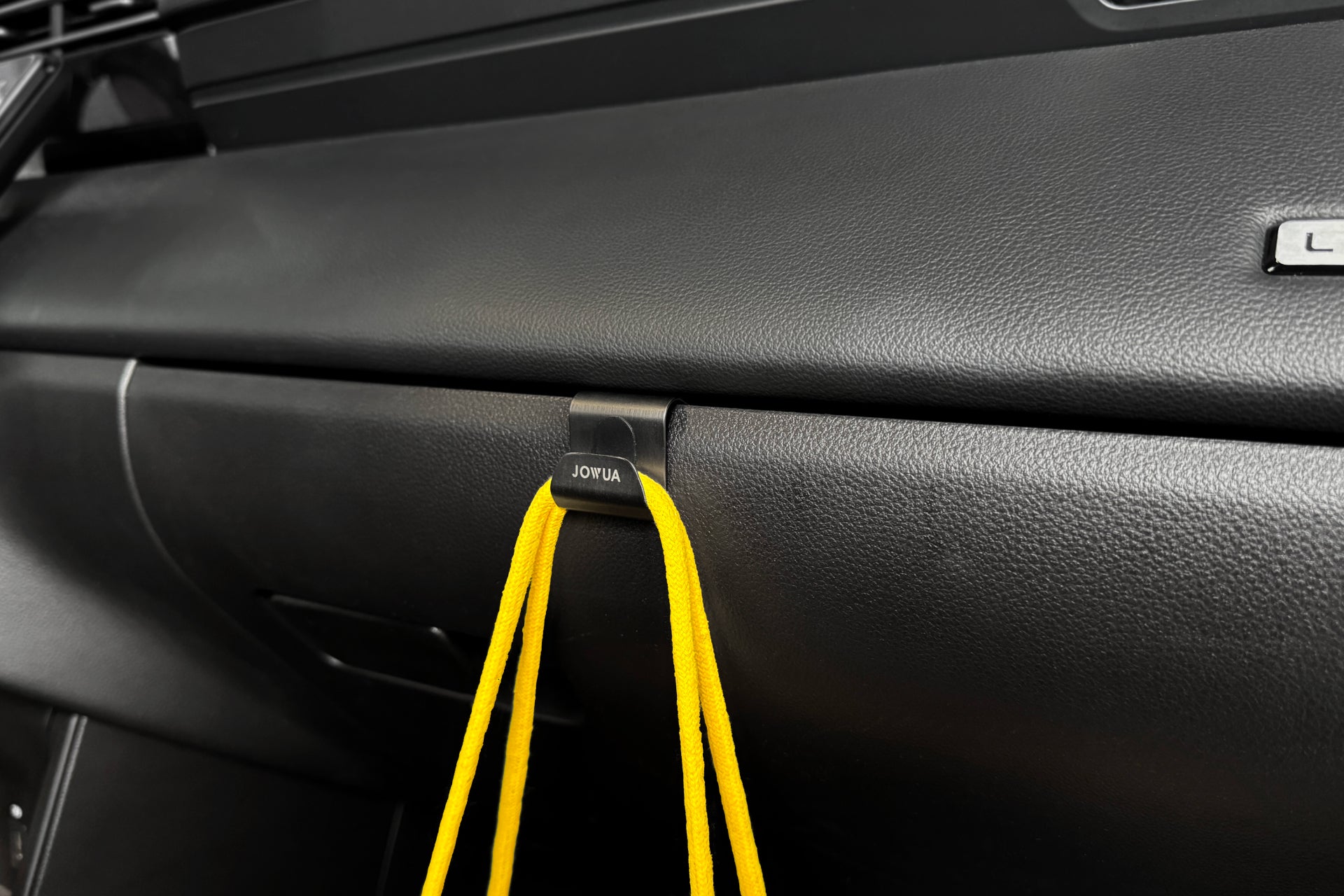 儀表板上組裝了來自 JOWUA Taiwan 的黑色 LUXGEN n⁷ 手套箱掛鉤,優雅地展示著亮黃色的線束。其獨特的設計可確保穩定性並防止滑倒,為您的汽車內裝提供實用且時尚的感覺。.