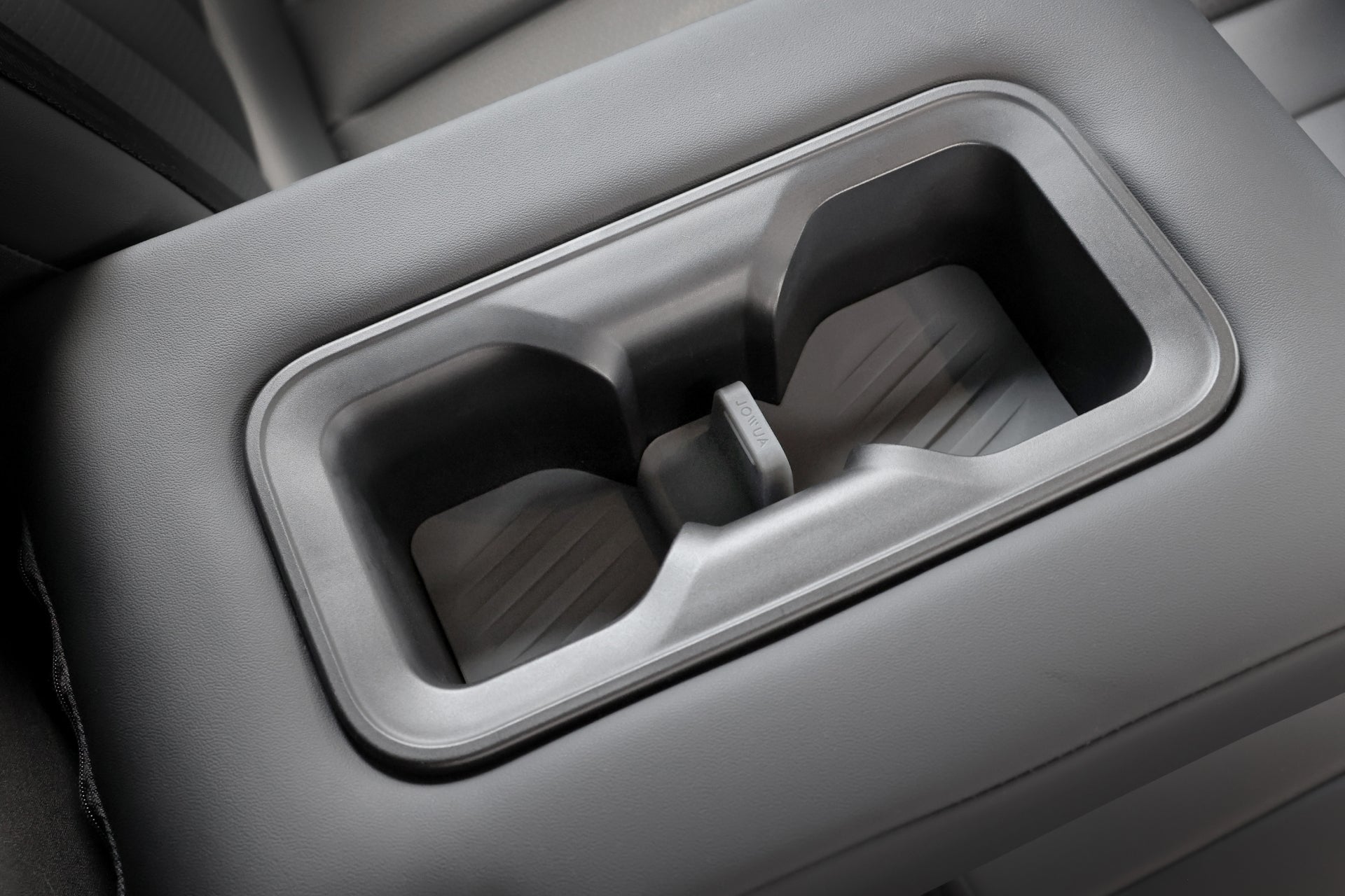 Luxgen n⁷ 汽車內裝特寫,配有兩個時尚杯架,是適用於 n⁷ 和 n⁷ LR 車型的 JOWUA 台灣杯架組的一部分。其現代設計融入灰色扶手中,包括紋理表面和矽膠杯架,可增強抓地力,展現出優質的汽車配件品質。.