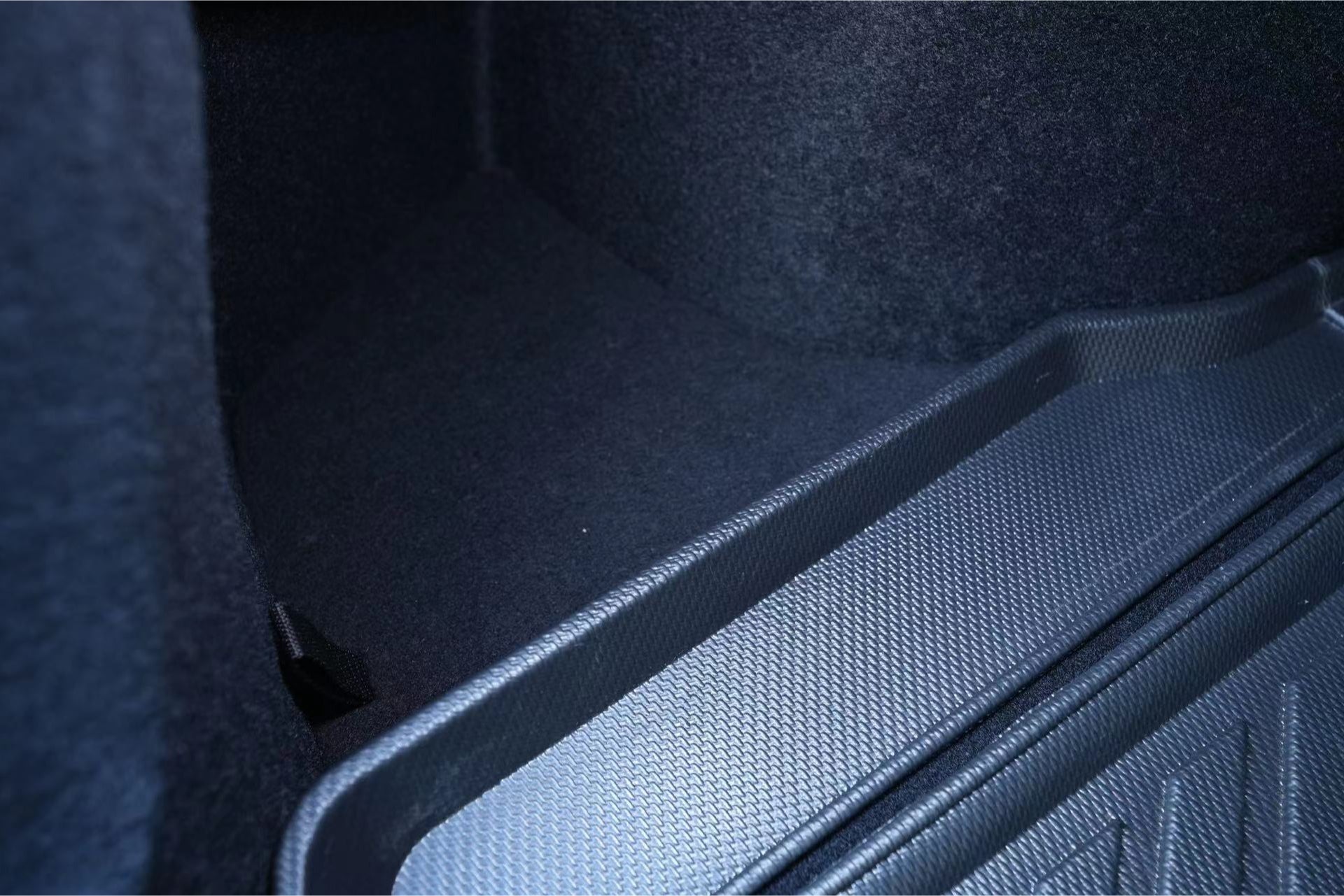 Tesla Model 3 行李箱採用黑色紋理地板,右側貼合塑膠墊,清晰展示 JOWUA 台灣行李廂訂製組合(Model 3,2024+煥新版)材質,為您的必需品提供出色的備品收納方案。.