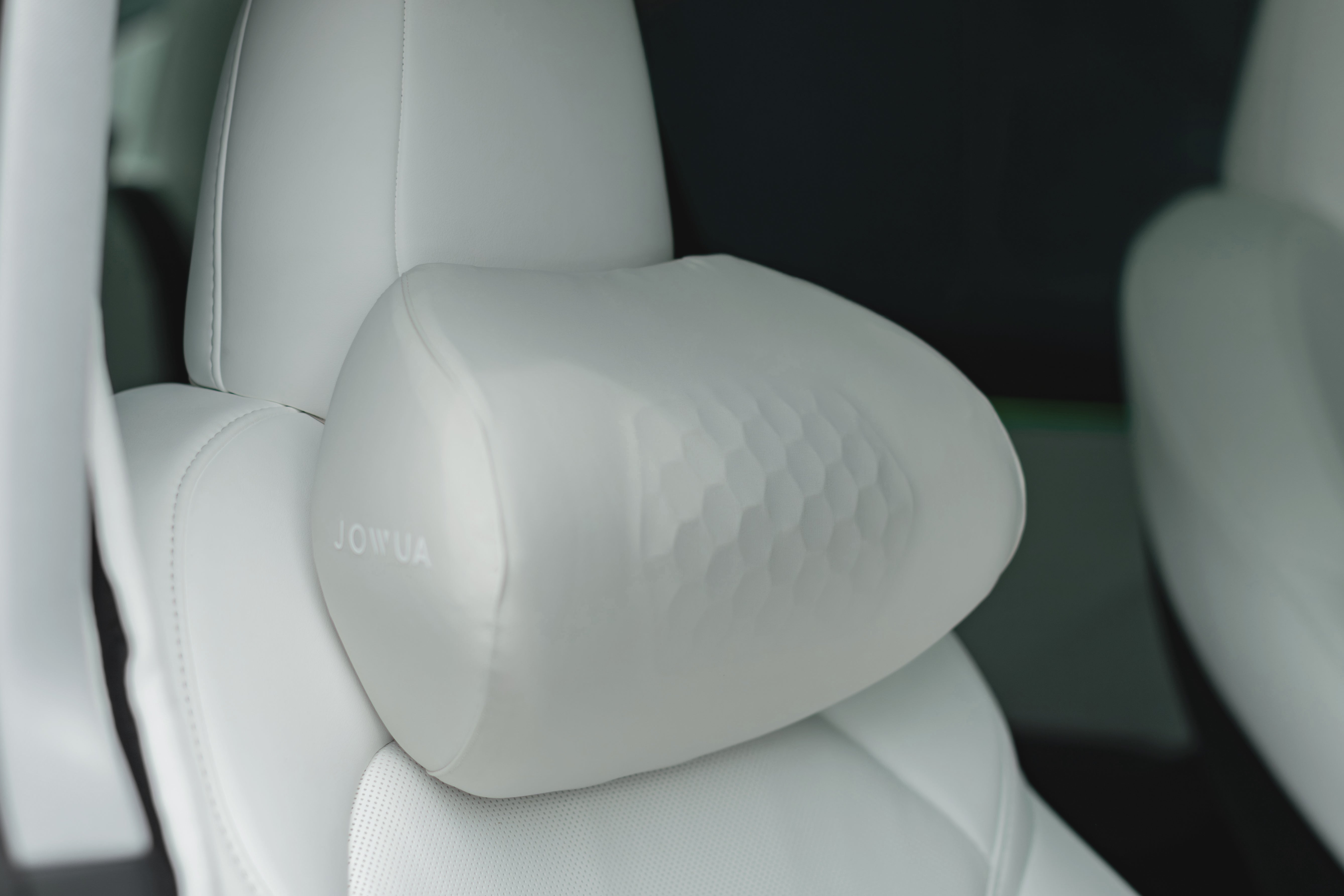 汽車座椅特寫,淺色、光滑的 JOWUA Taiwan 車用頭枕(兩入/一入)附在頭枕上,提供舒適的人體工學支撐。連接到頭枕,提供舒適的人體工學支撐。.