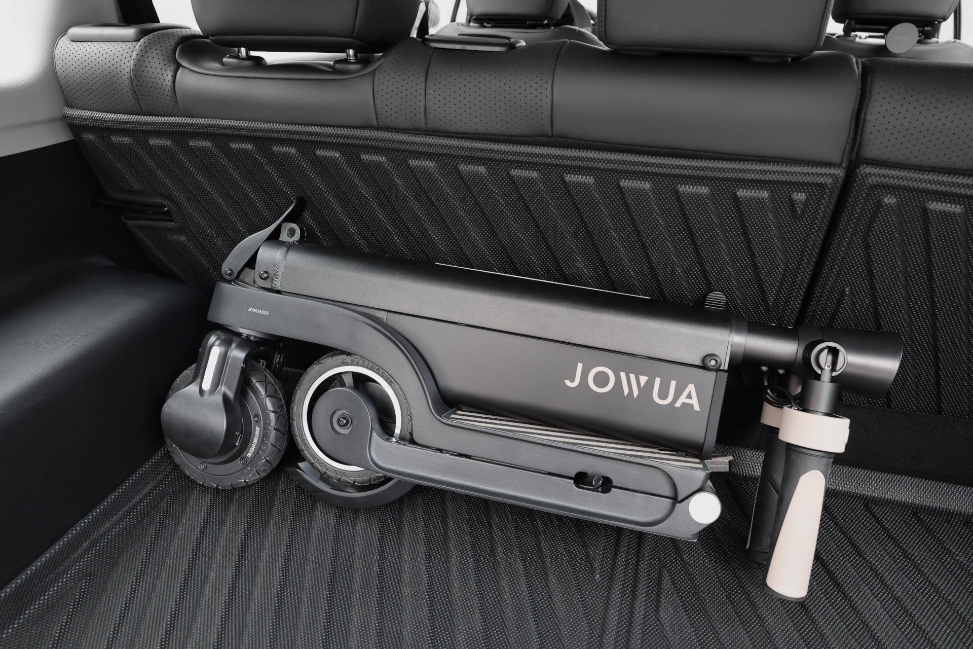台灣 JOWUA 的小型折疊式黑色電動代步車可放置在汽車的貨運區,由立體防水行李廂墊+椅背墊組合 (LUXGEN n⁷ 5人座) 和時尚的黑色內裝保護。.
