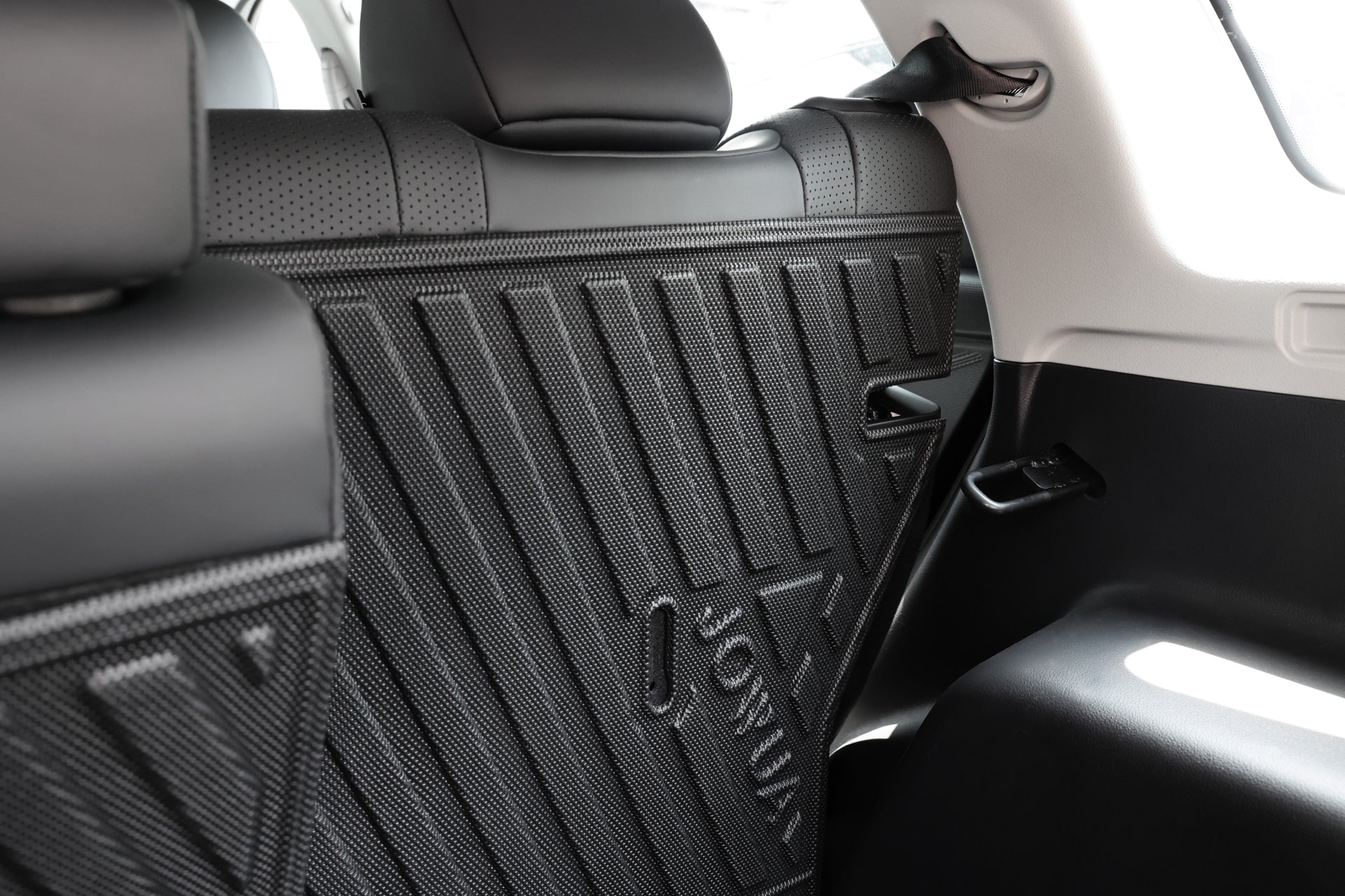 一輛現代車輛的後座及貨物區隔板特寫,以 JOWUA Taiwan 的立體防水行李廂墊+椅背墊組合為 LUXGEN n⁷ 5 人座,黑色紋理設計與品牌,光線穿透側窗。.