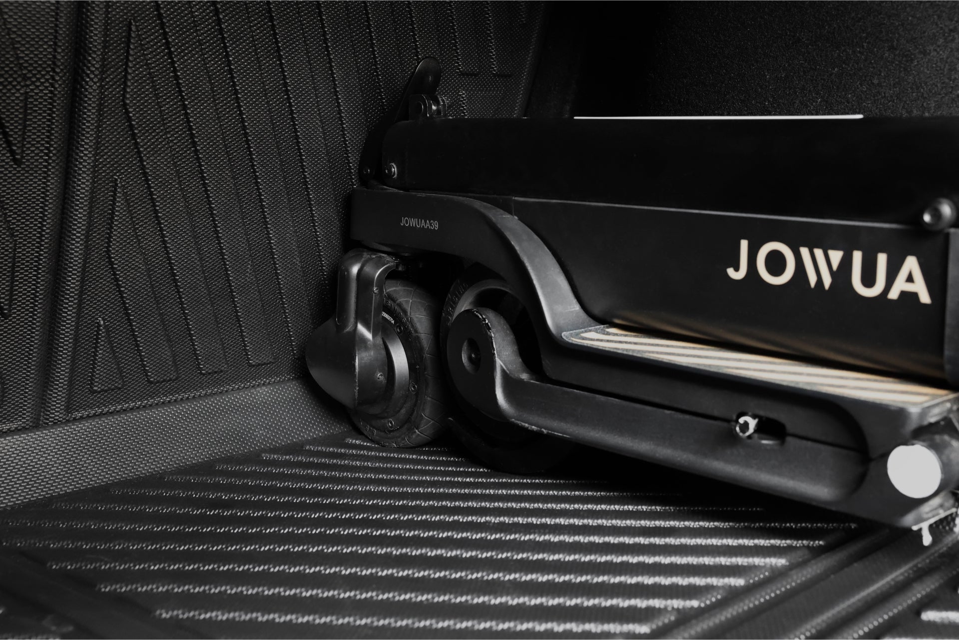 JOWUA 台灣的折疊式黑色電動滑板車靠在羅紋表面上,讓人想起 2024+ Model 3 中發現的創新行李廂官方組合。.