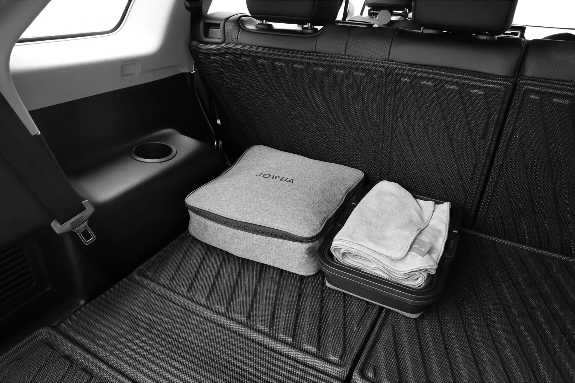JOWUA 台灣防水第二排椅背墊 (LUXGEN n⁷ 7 人座) 採用帶紋理的黑色 TPE 材質墊,可有效容納灰色旅行包和折疊毛巾。憑藉其可折疊後排座椅和防水防水保護,它為圓形杯架或儲物空間提供了完美的空間。.