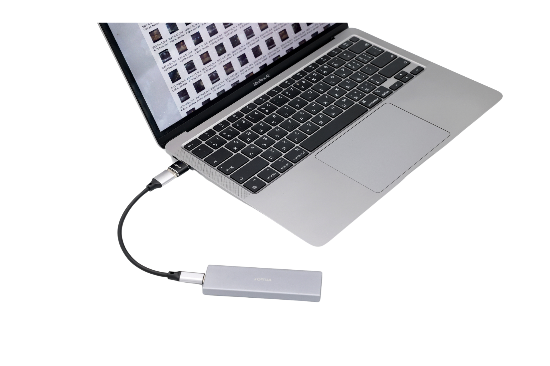 帶有棋盤螢幕的筆記型電腦透過 JOWUA Taiwan 的哨兵讀組 USB-A 轉 Type-C 連接線(包含 OTG 功能)連接到灰色、耐用的外部硬碟。硬碟位於筆記型電腦的前方。.