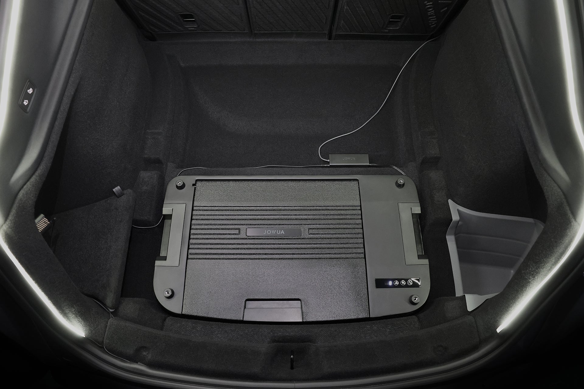 圖中為一輛裝有 JOWUA Taiwan Type-C 車用行動冰箱 (Model Y 全車系) 的汽車的貨運區,右側是數位顯示器和連接線,四周鋪有深色地毯,右側是一個小垃圾桶。.