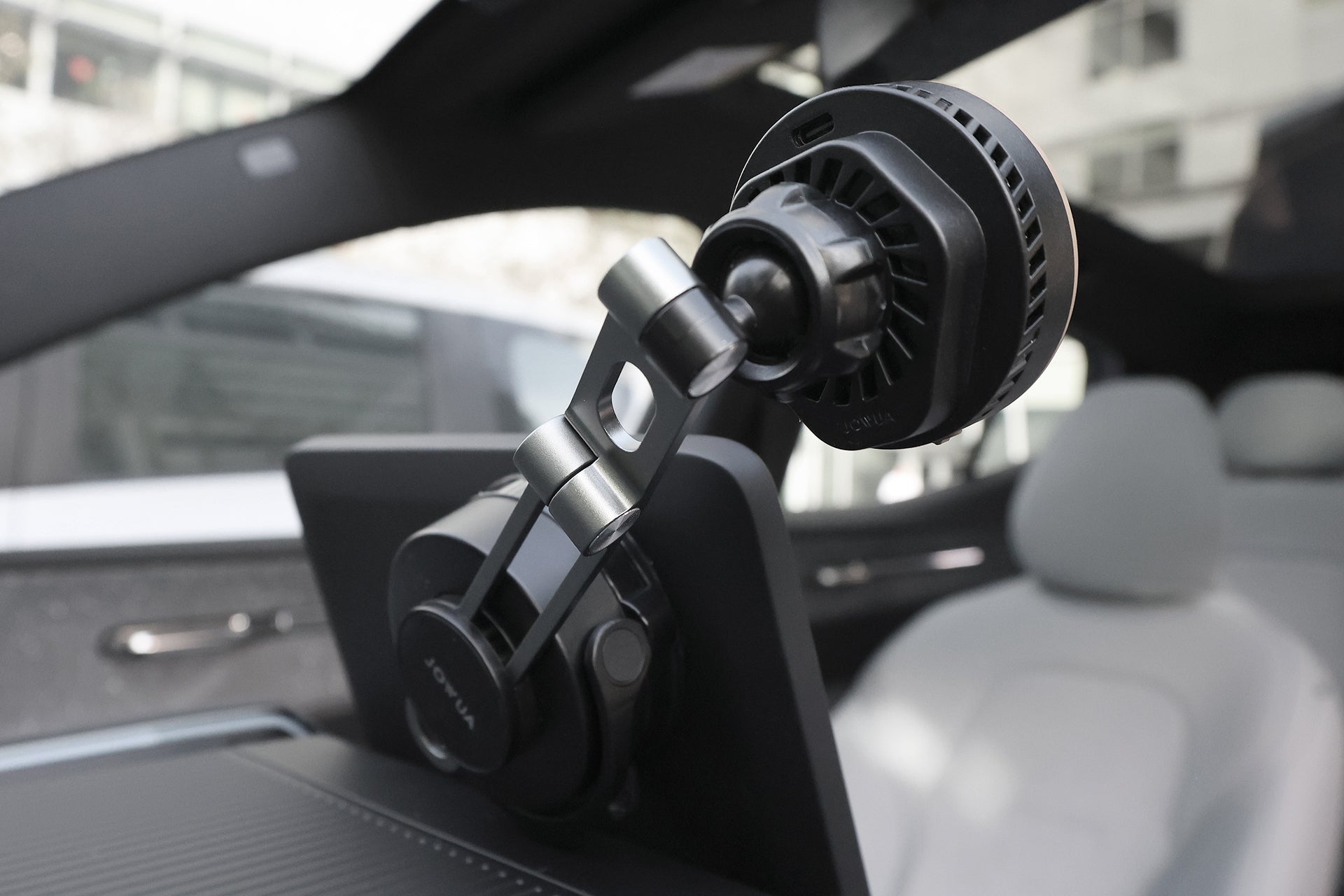 白色時尚內裝的現代汽車儀表板上的攝影機或感應器特寫,顯示座椅的一部分,背景為 JOWUA Taiwan Qi2 製冷六維隱藏車架 (MagSafe 款) 配件。.