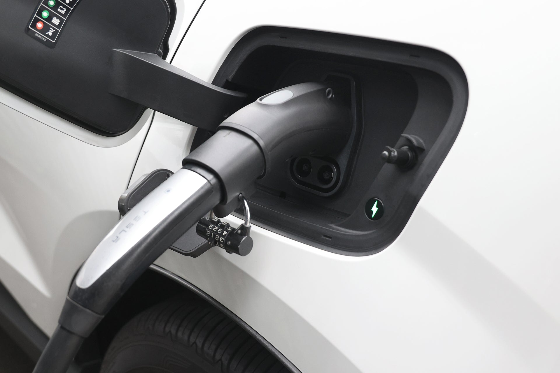 白色汽車電動車充電口特寫,附綠燈及電線。插座上使用 JOWUA Taiwan CCS1 快慢充萬用組,方便與各種充電器連接。.