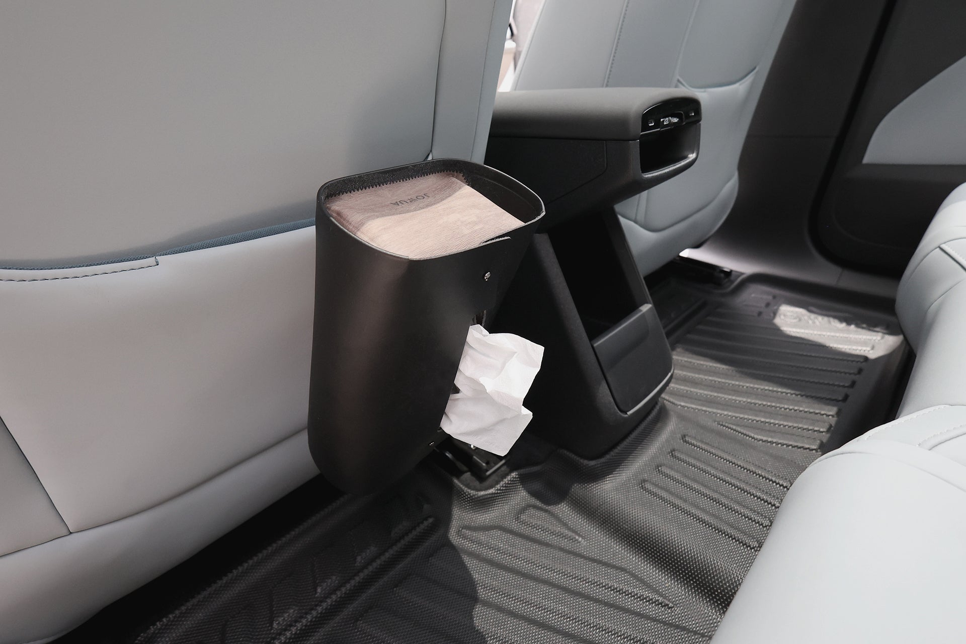 淺灰色車座上附有黑色紙巾架,紙巾清晰可見。Volvo EX30 的內裝採用 JOWUA Taiwan 立體防水腳踏墊,提供專利收納設計全面防護。.