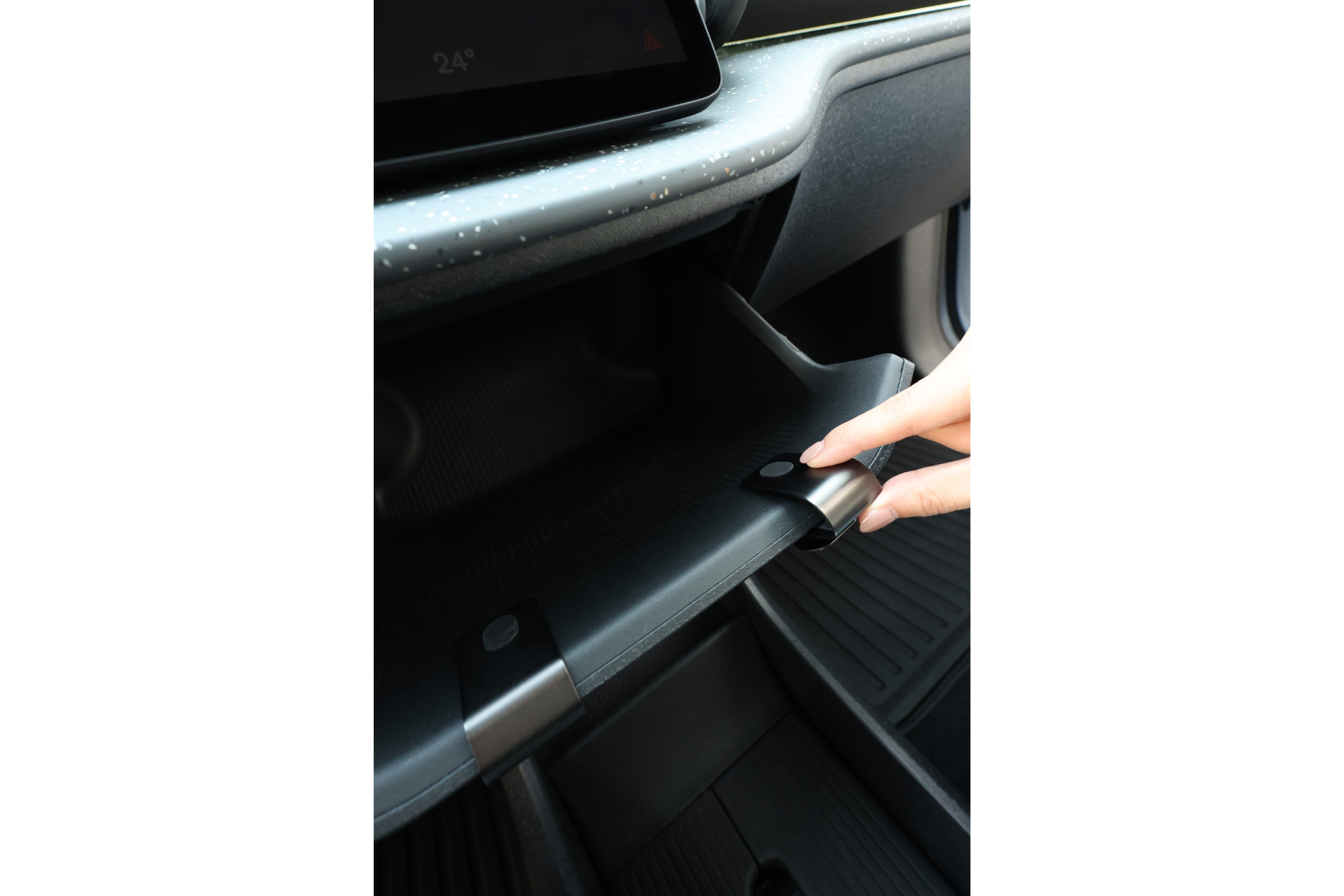 一隻手按下按鈕打開 Model 3/Y 煥新版 JOWUA Taiwan 手套箱掛鉤,上方可見儀表板、觸控螢幕和時尚的 Tesla 車用收納細節。.